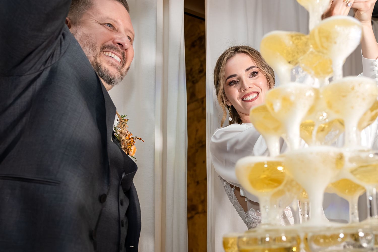 Champagne being poured into a tower of crystal glasses creating a cascading effect at a celebration.