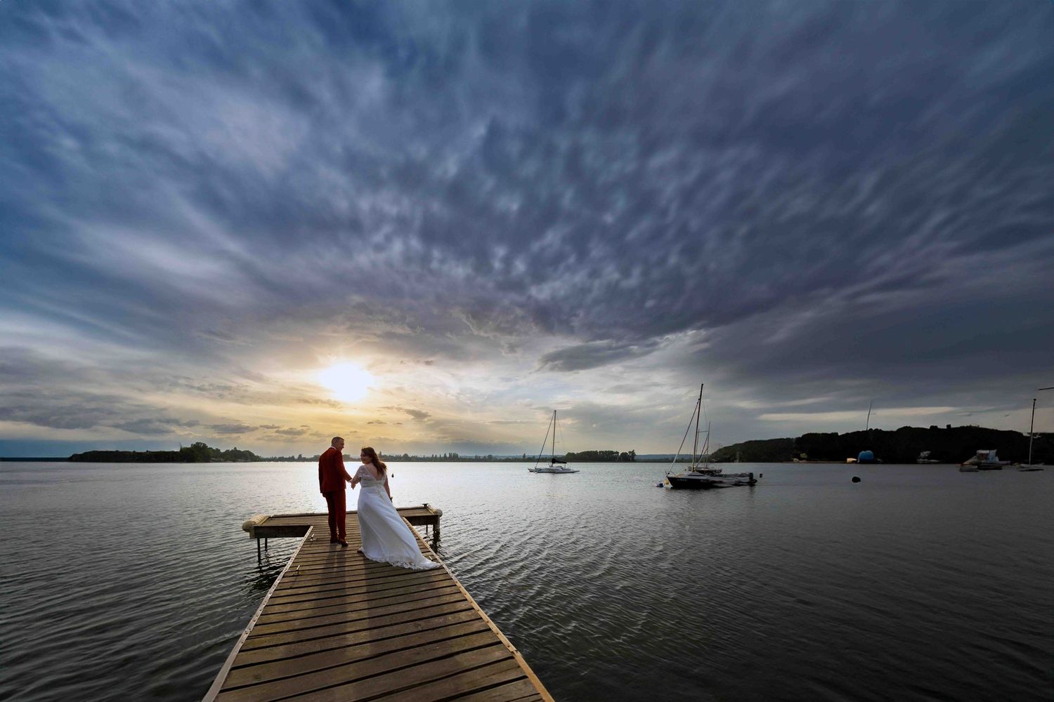 couple de mariés en noir et blanc sur le ponton du grand large meyzieu au couché de soleil