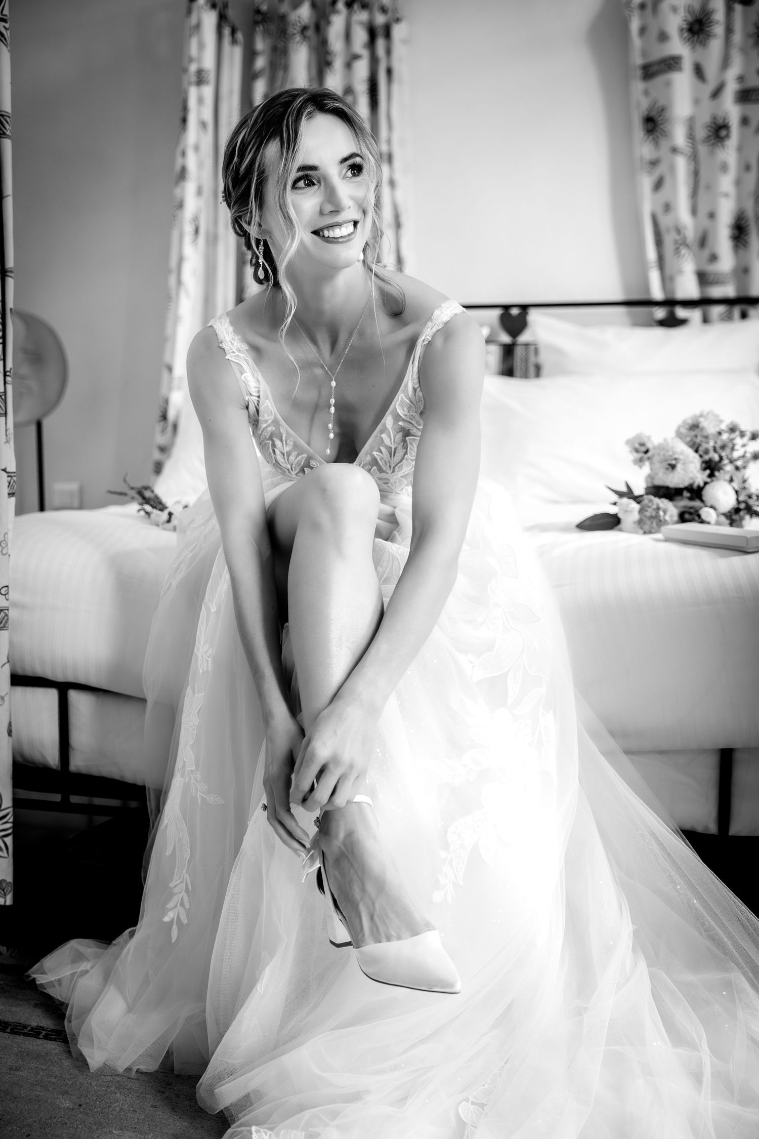 Elegant bride in white lace gown poses for romantic black and white bridal portraits.