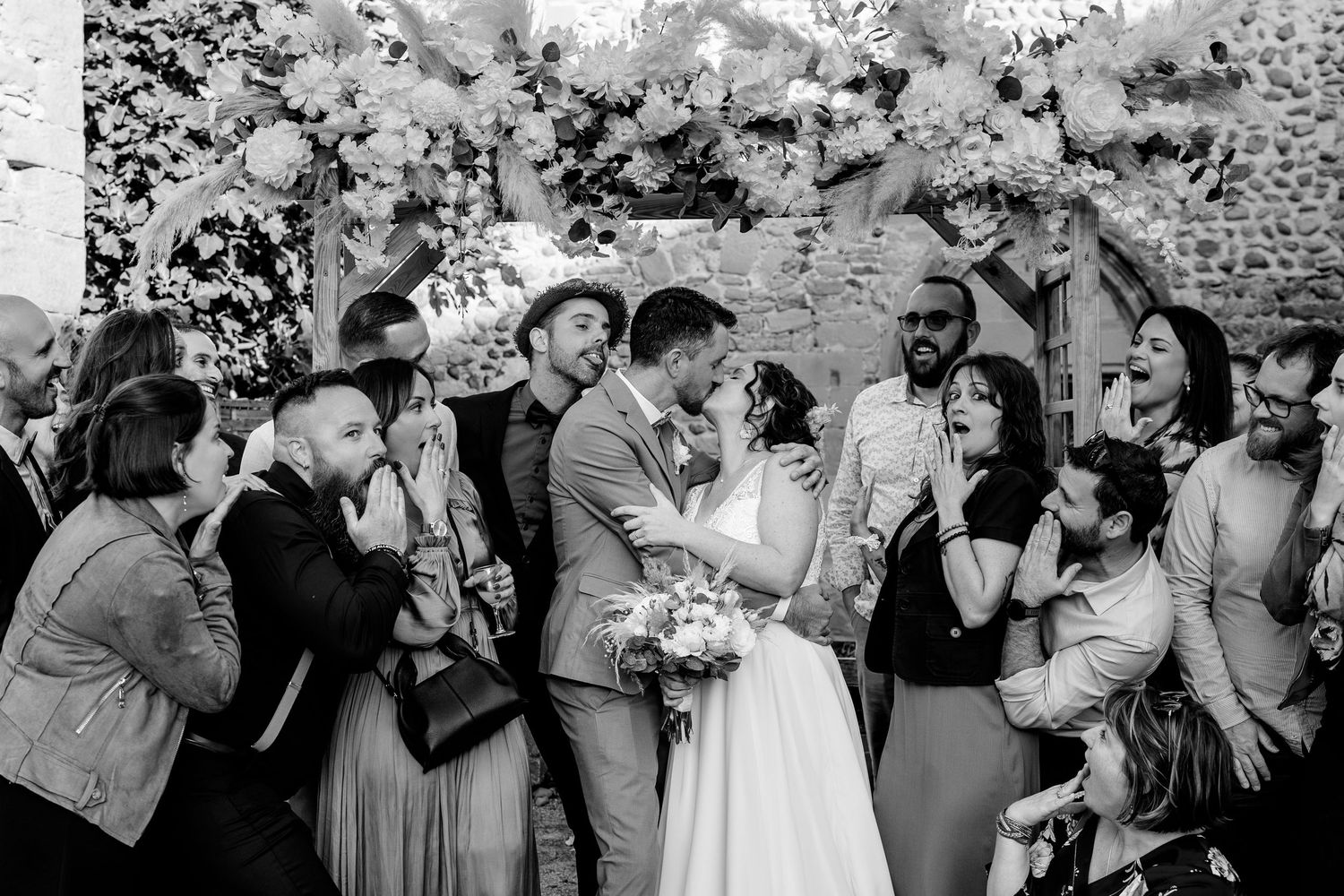 Wedding guests share intimate kisses during an outdoor celebration.