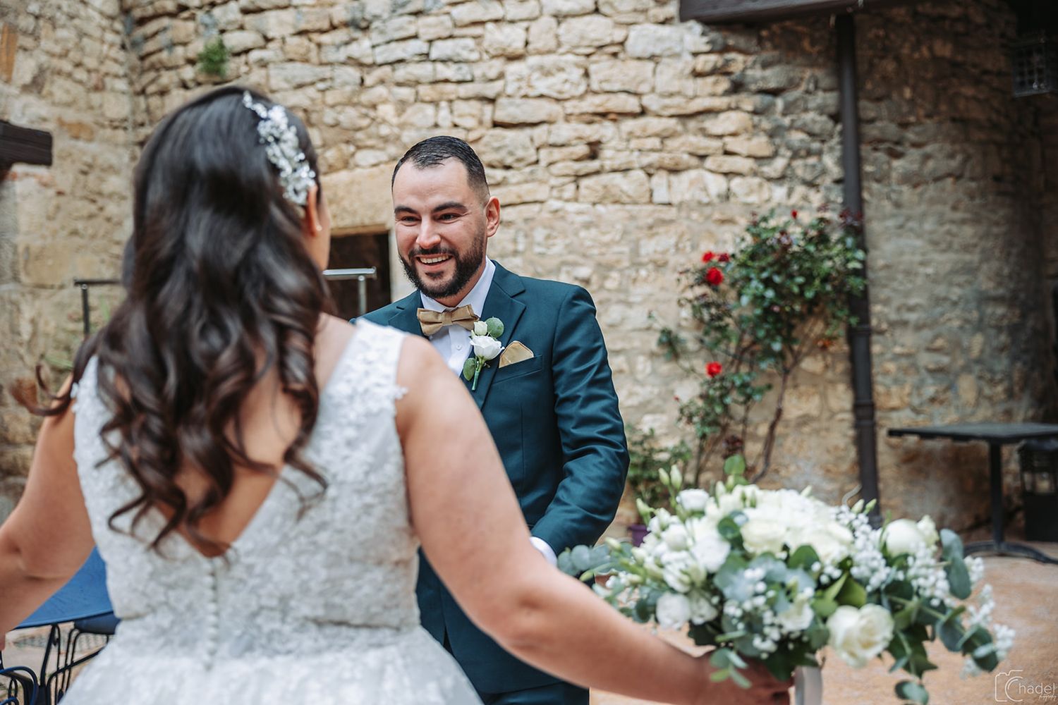 Joyful wedding celebration with laughter and hugs between guests at a rustic stone venue.