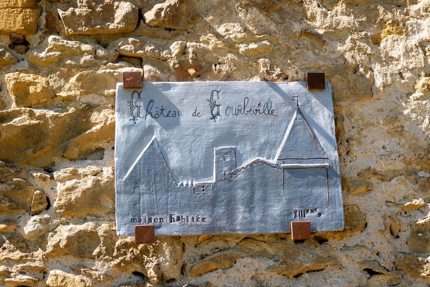 A rustic stone wall with blue painted text or writing visible on sections of the weathered surface.