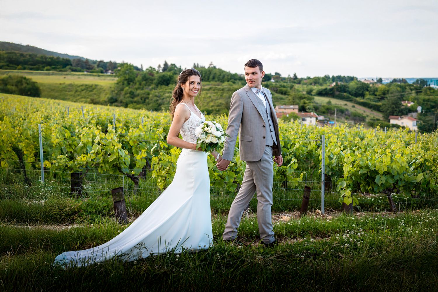 couple main dans la main marchent dans les vignes du château du Pin à Morancé