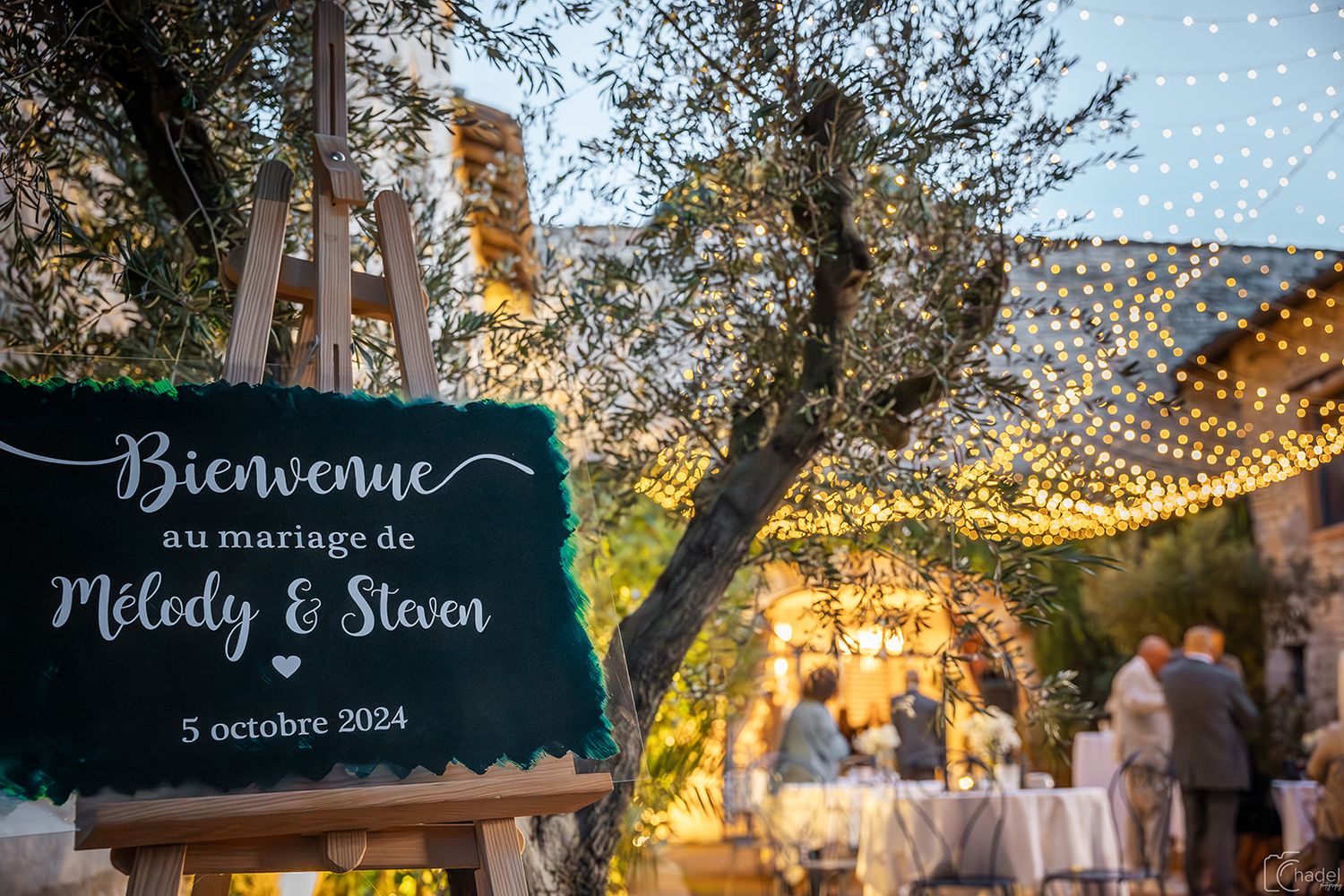 Rustic outdoor wedding reception venue decorated with twinkling string lights and lanterns at sunset creating a magical ambiance.