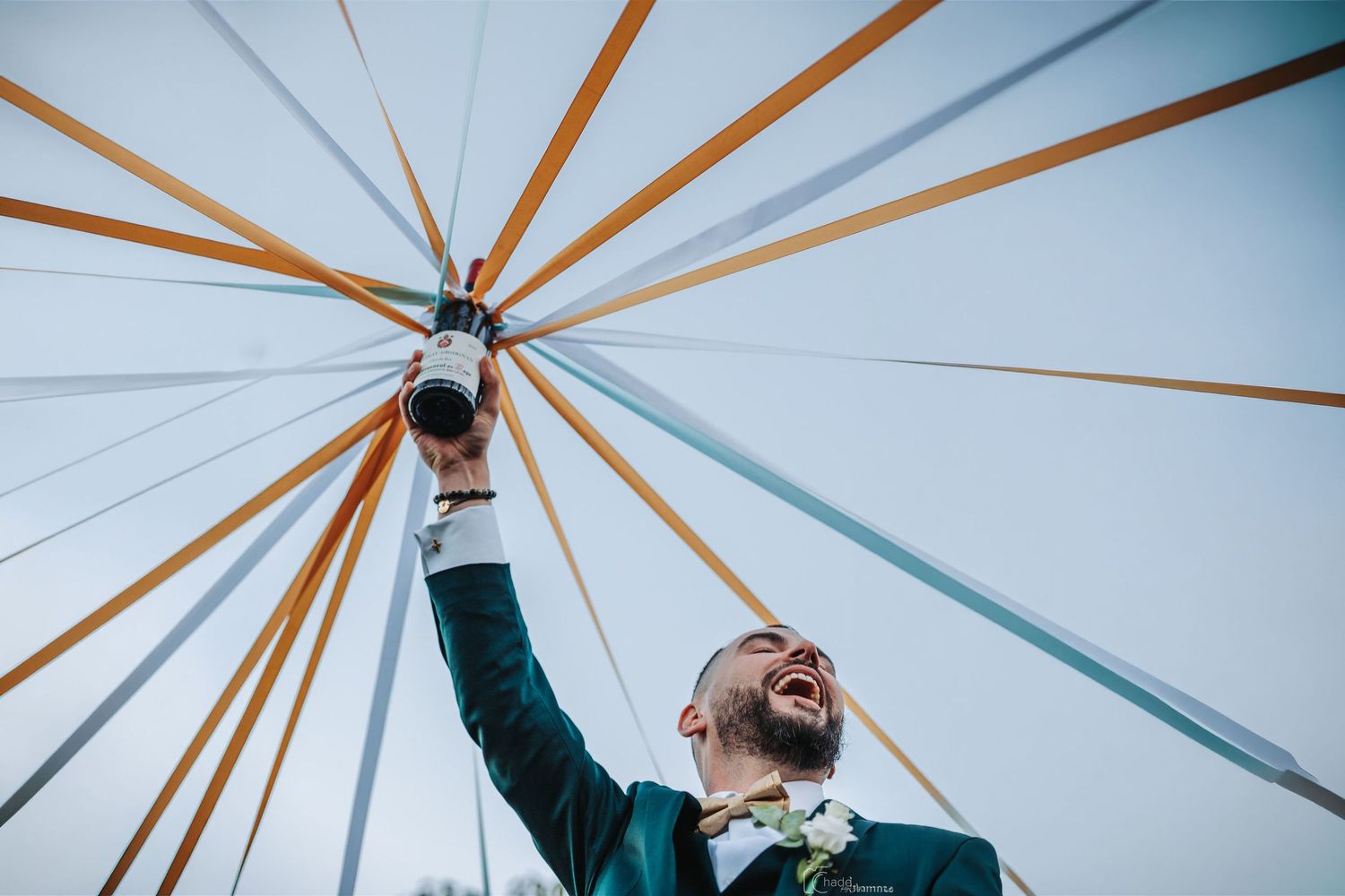 A person laughs joyfully while spinning beneath a geometric canopy structure with radiating wooden beams and white panels.