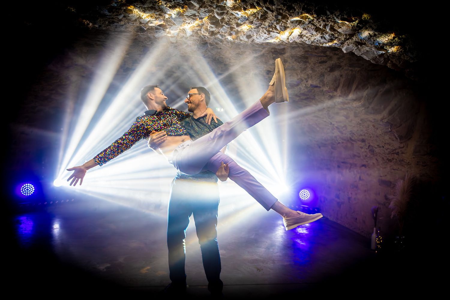 A dancer performs dramatic movements in a dark space illuminated by bright blue and white spotlights.