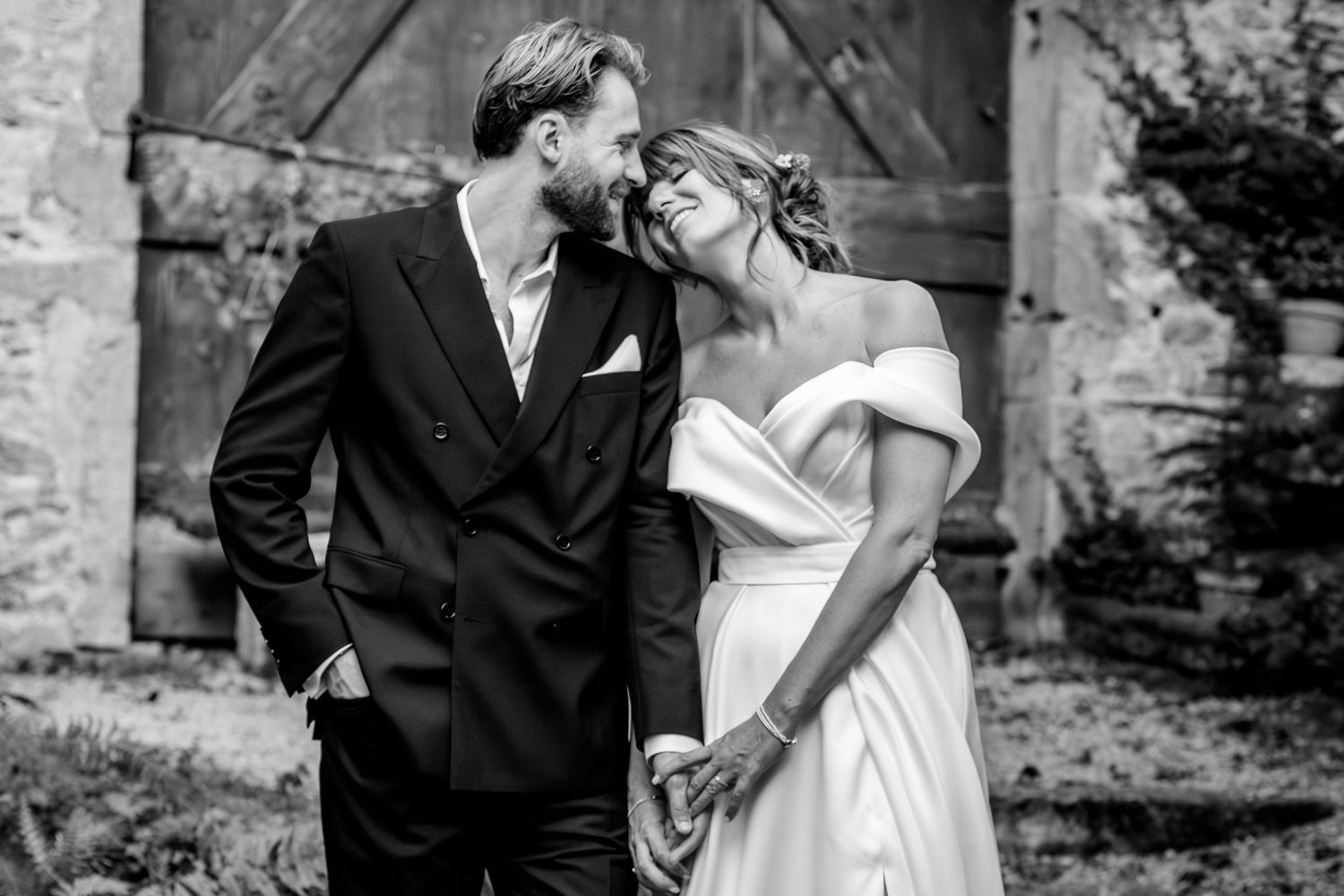 Elegant black and white wedding portraits against rustic stone wall backdrop.