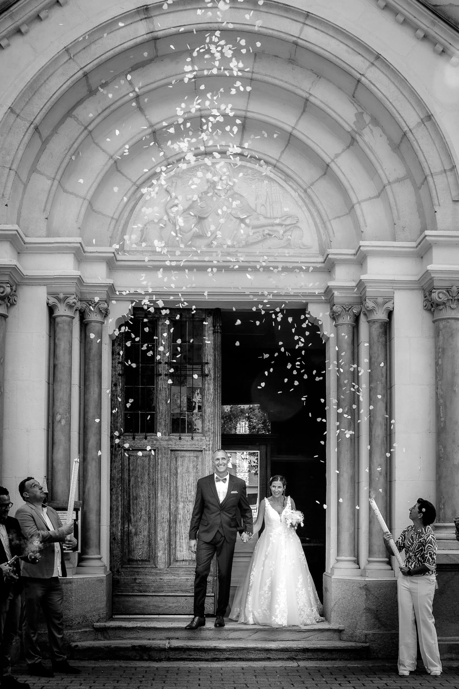 A series of black and white wedding photos showing a couple under an elegant arched entryway with twinkling lights.