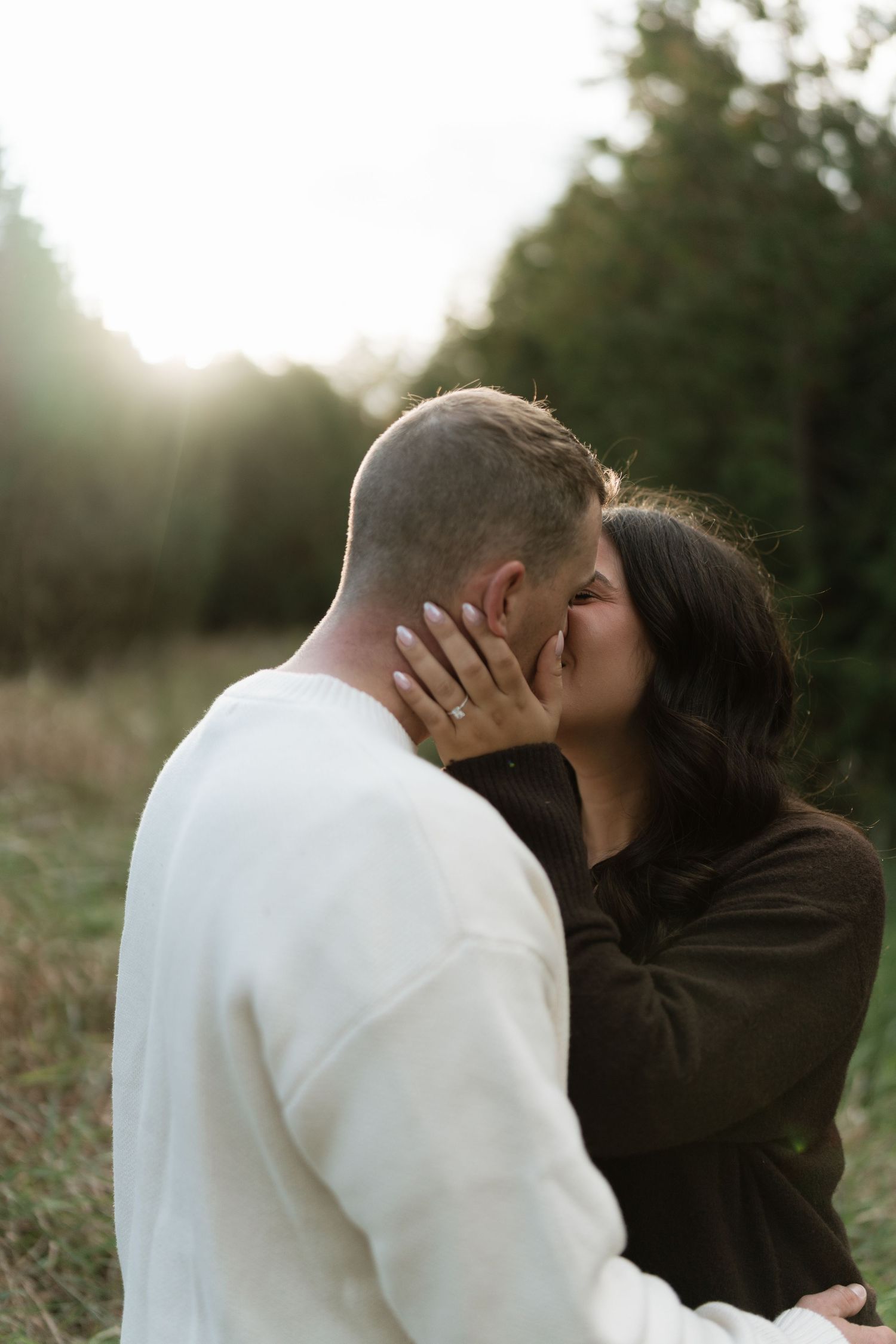 A tender moment between two people embracing in a sunlit outdoor setting.