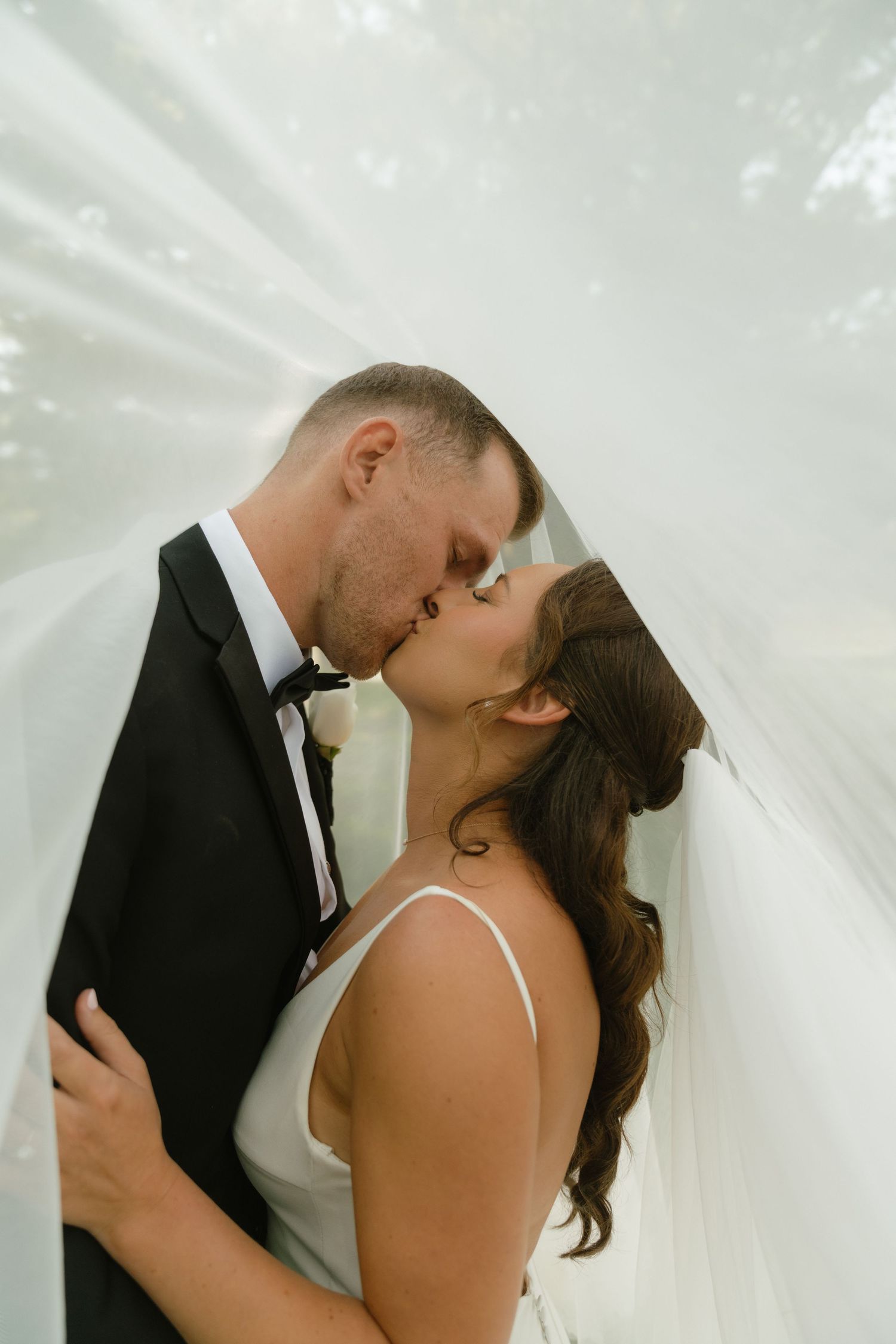 A romantic wedding moment captured under a flowing white veil.