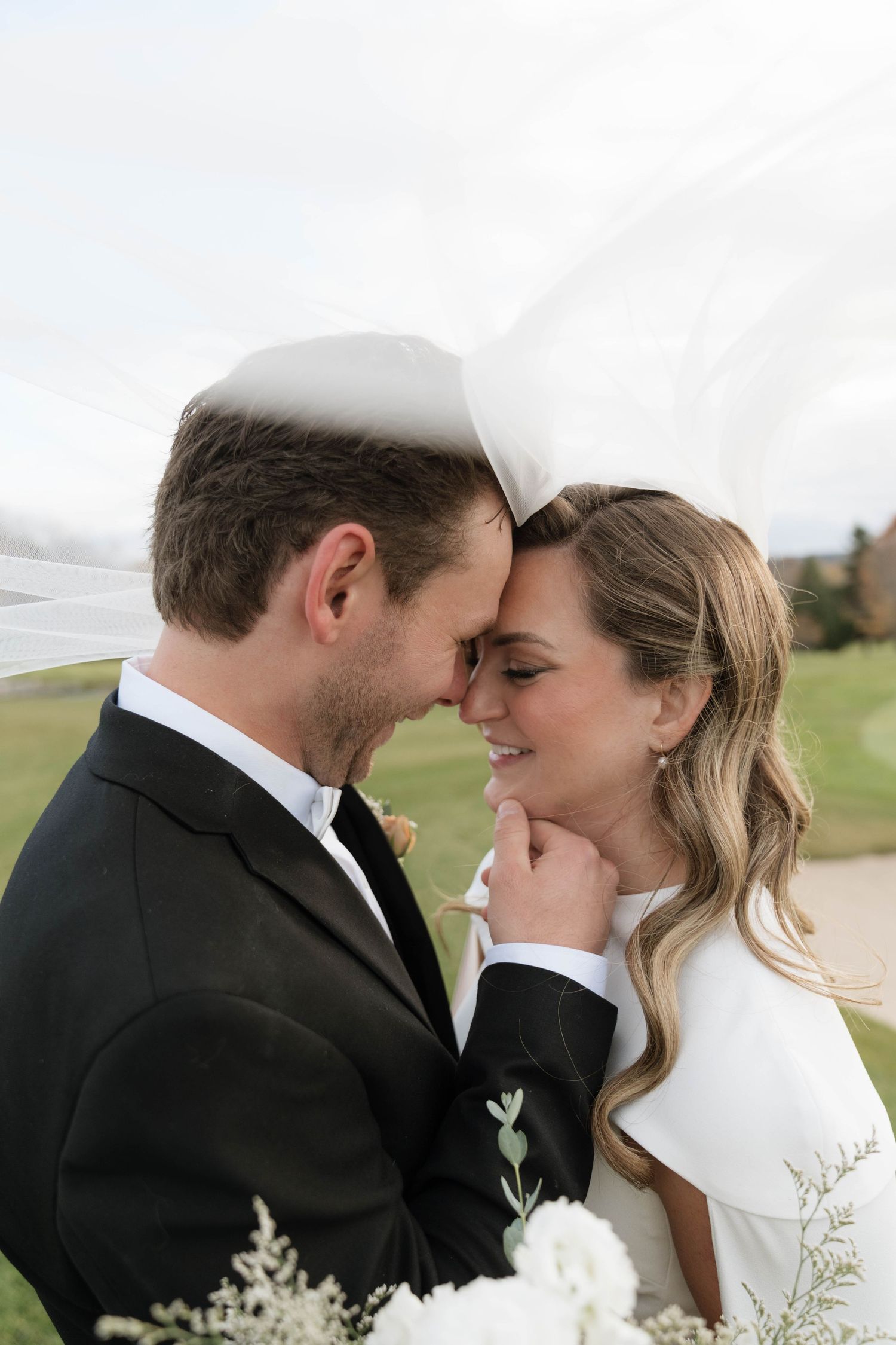 Intimate wedding portrait of couple sharing a tender moment outdoors.