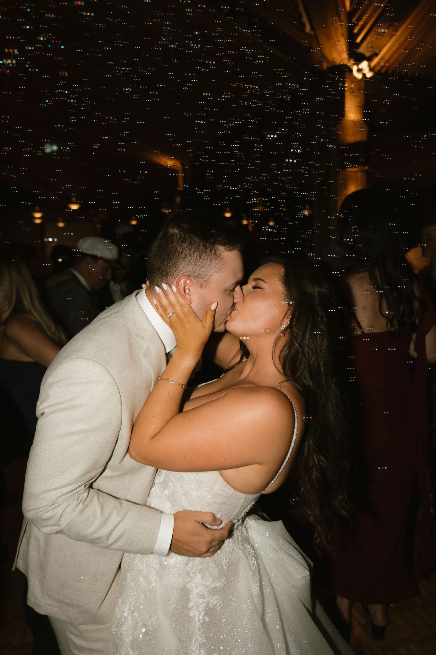 Romantic first dance under twinkling lights at wedding reception.