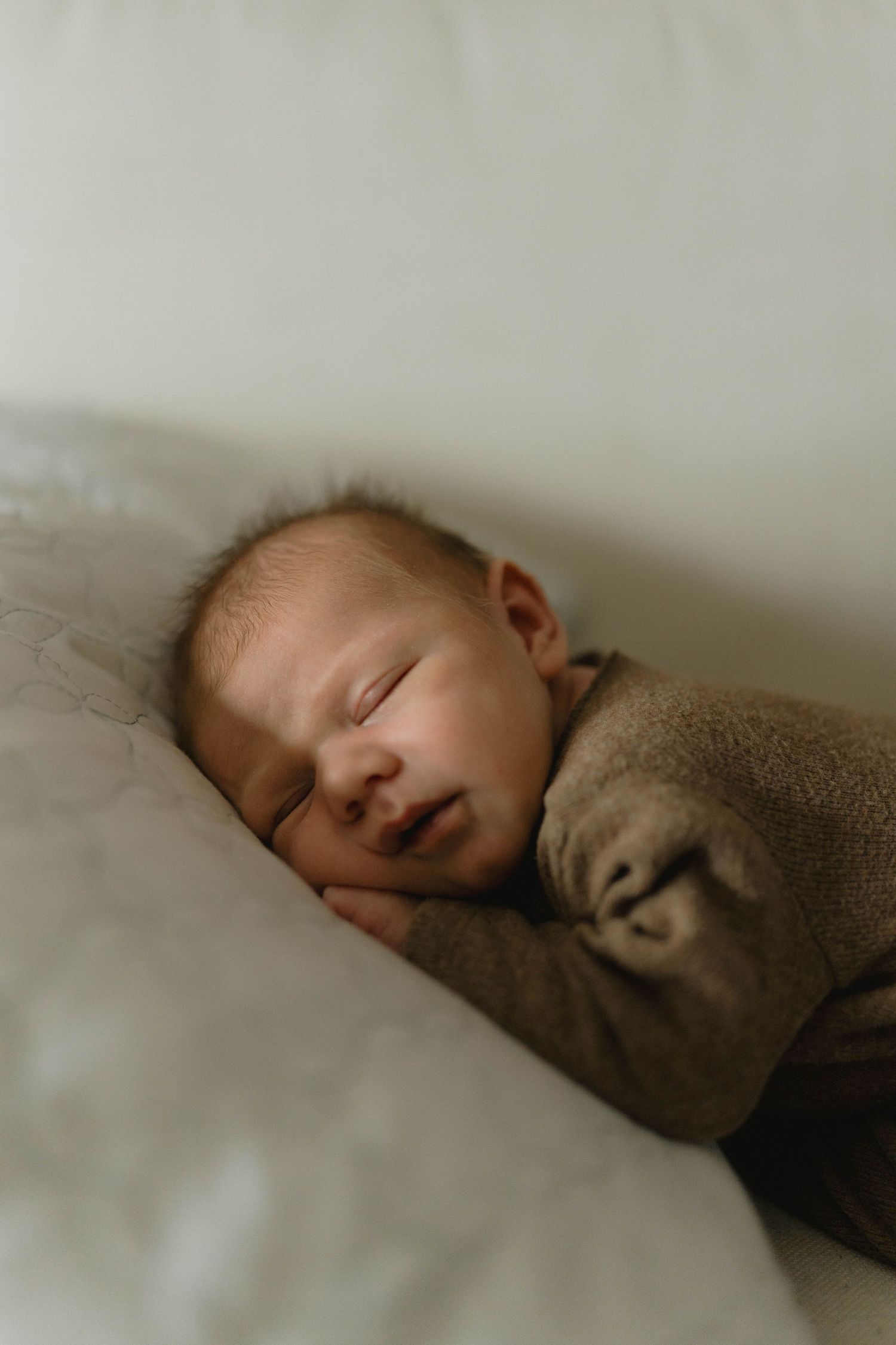 Peaceful sleeping baby wrapped in soft brown blanket.