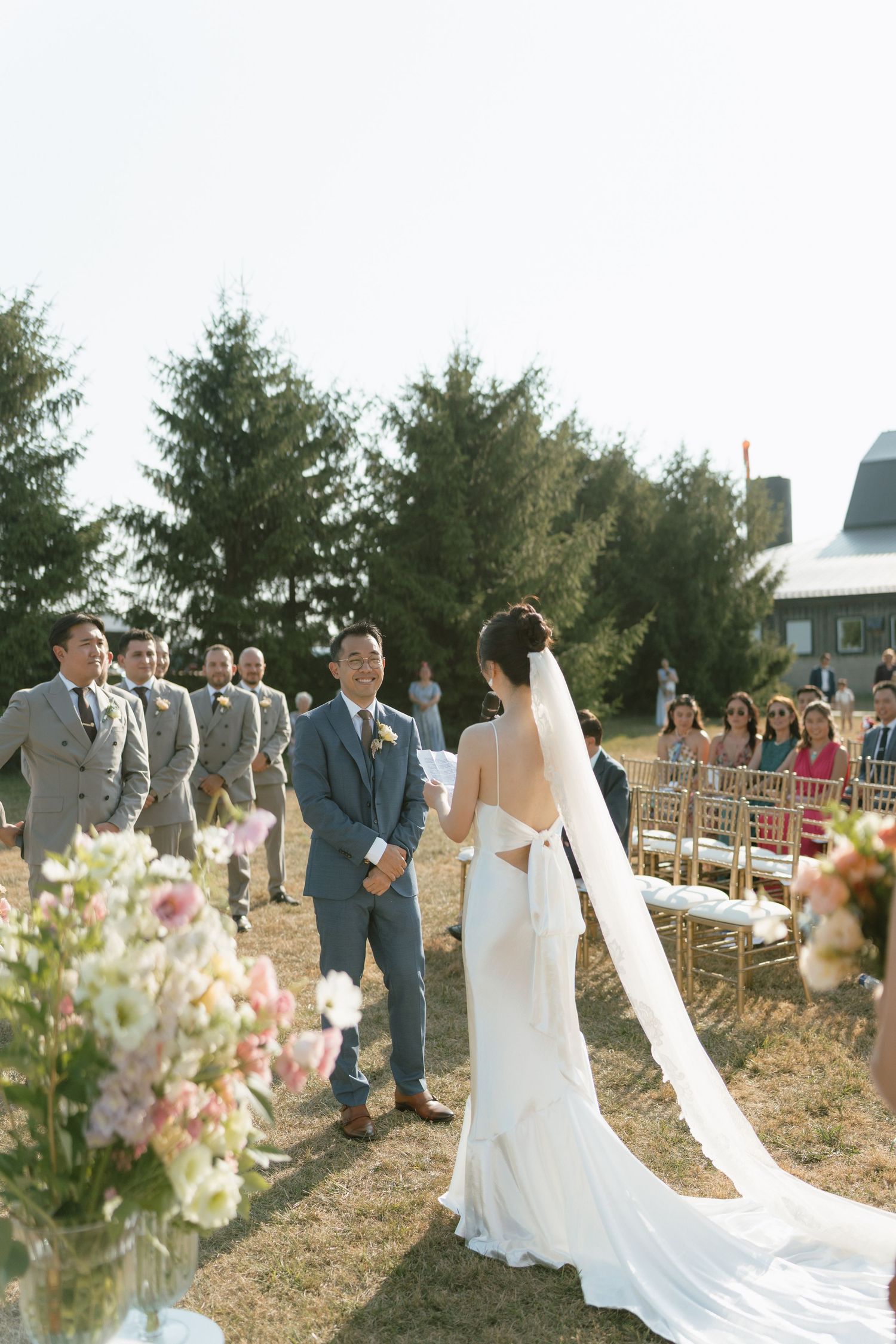 Outdoor wedding ceremony setup with white chairs and floral arrangements.