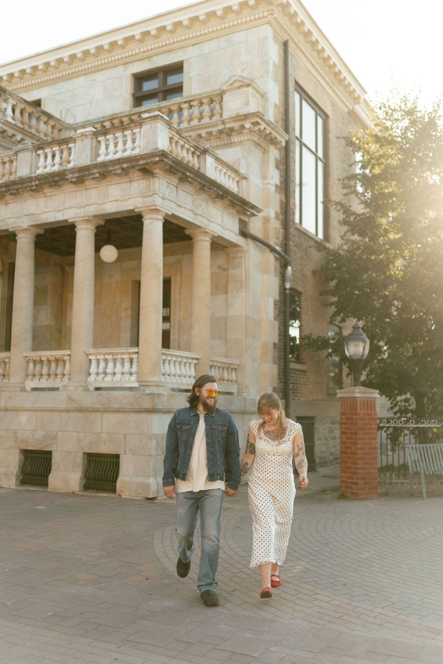 Couple walking together outside historic stone building with columns.