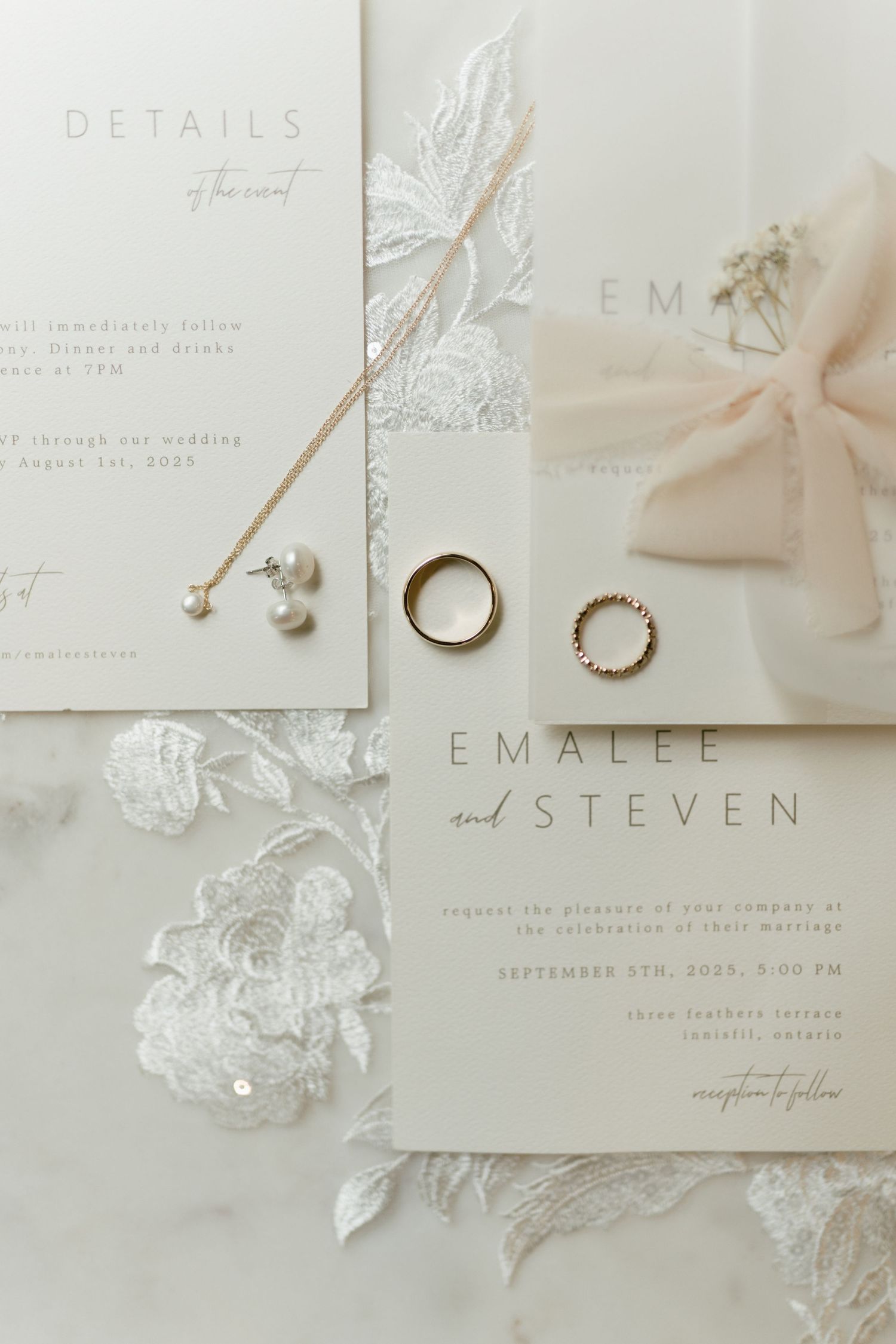 Elegant wedding invitation suite in white and silver with floral details and rings.