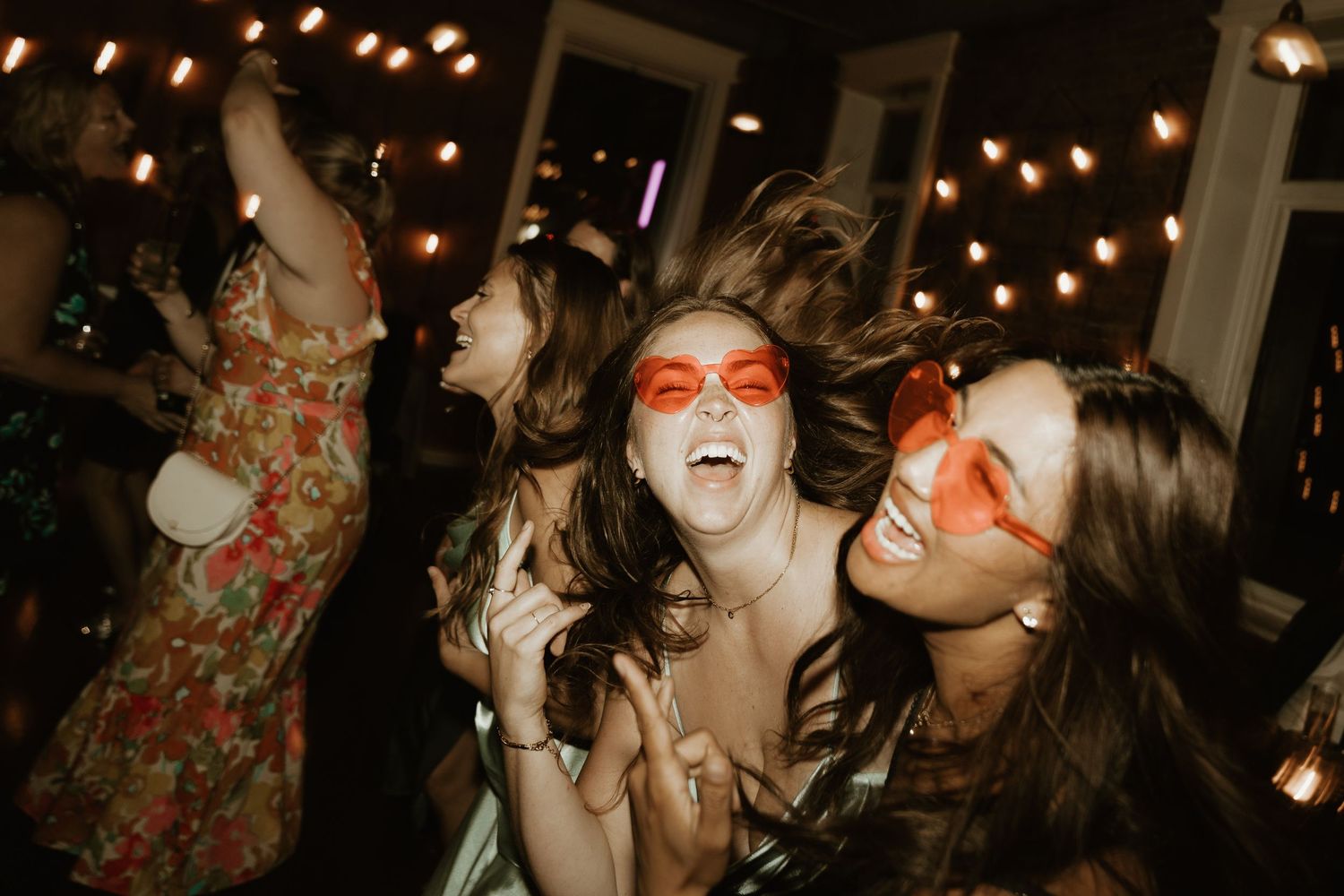Wedding guests dancing and celebrating under warm lighting at an indoor reception.
