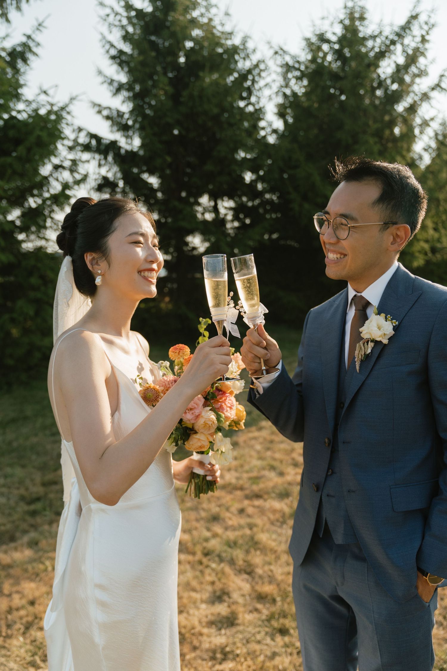 Wedding couple toasting with champagne glasses during golden hour celebration.