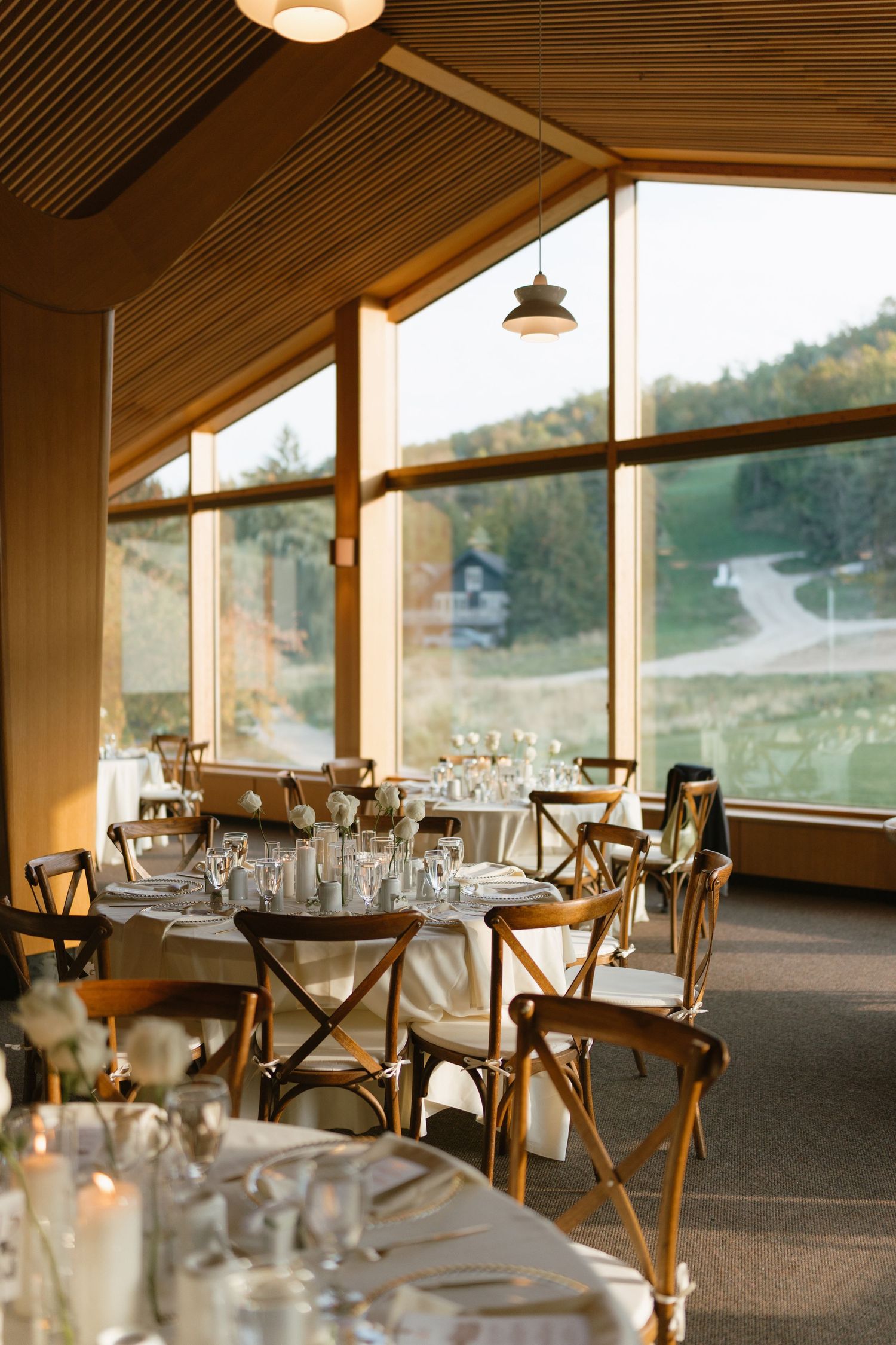 An elegant reception venue with wooden beams and tables set for a wedding celebration.