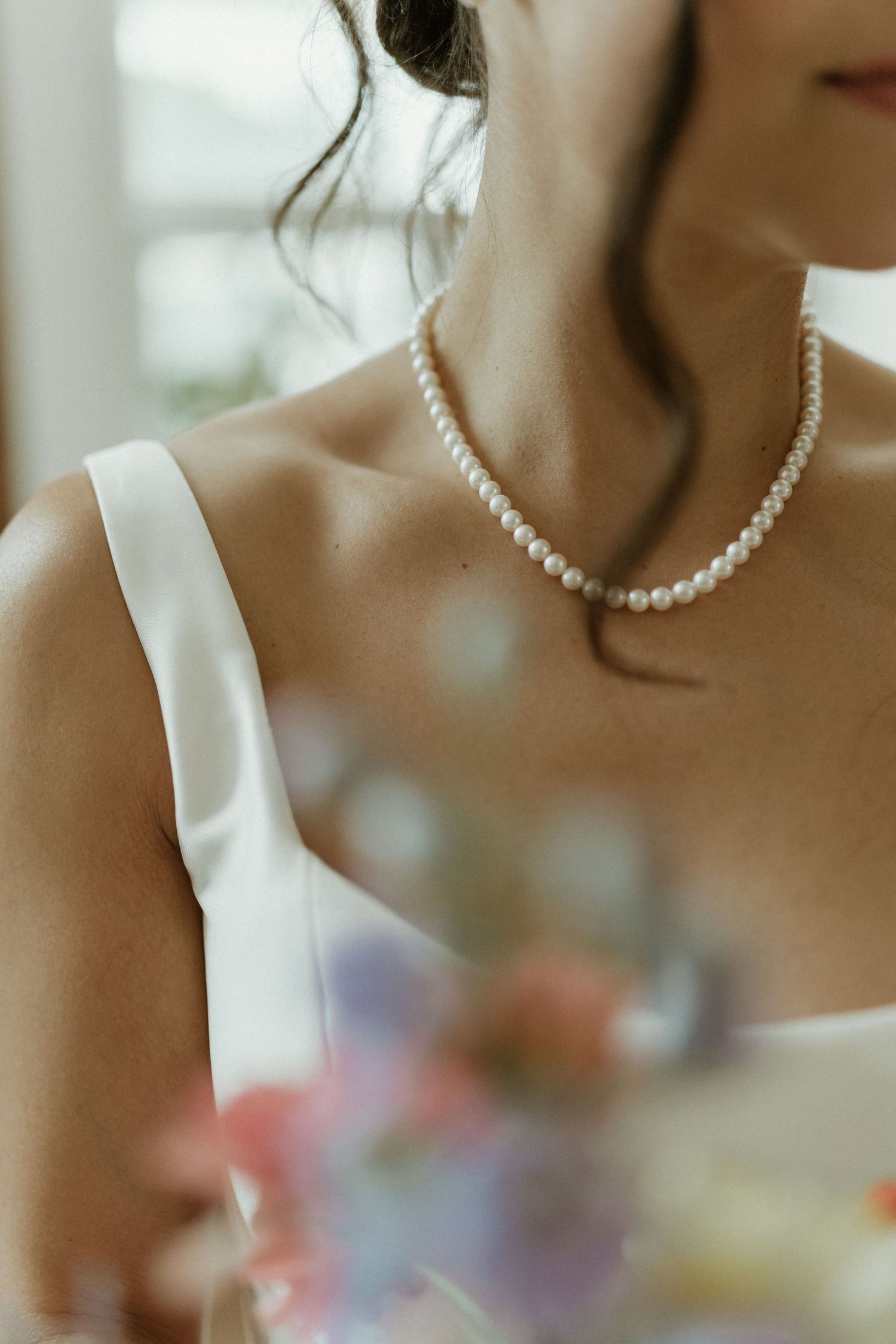 Close-up detail of a pearl necklace and white dress fabric.