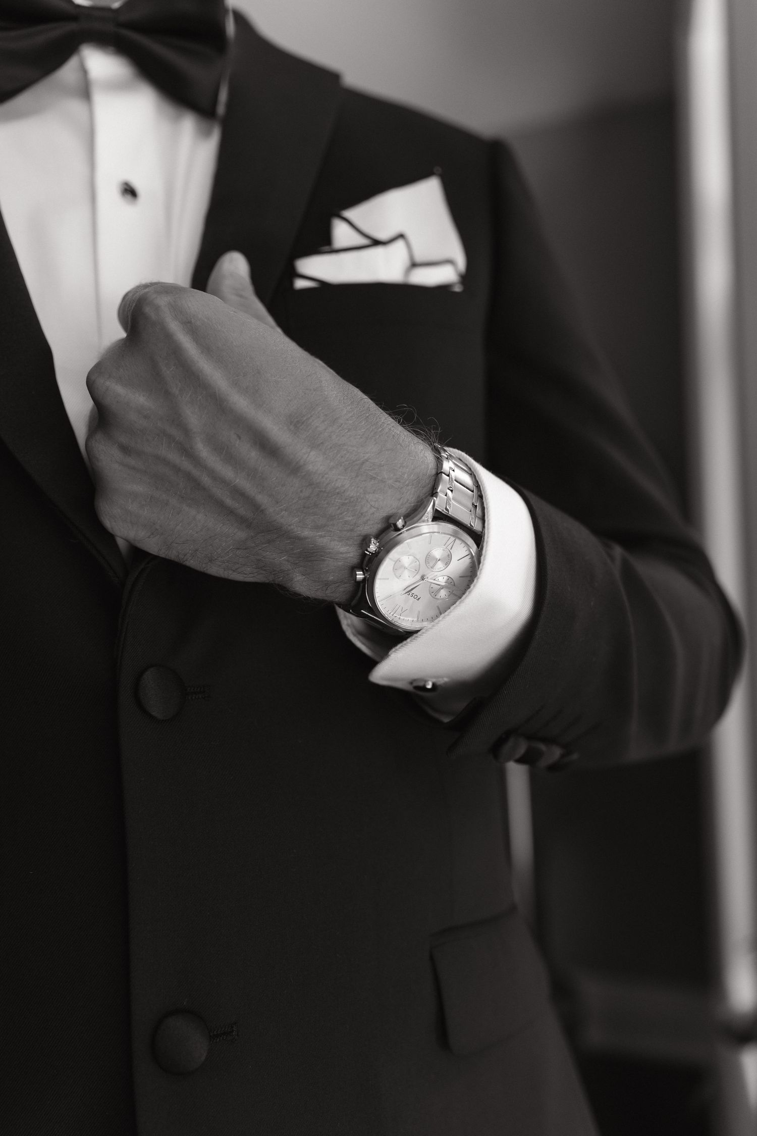 Close-up of groom's formal tuxedo with watch and pocket square.