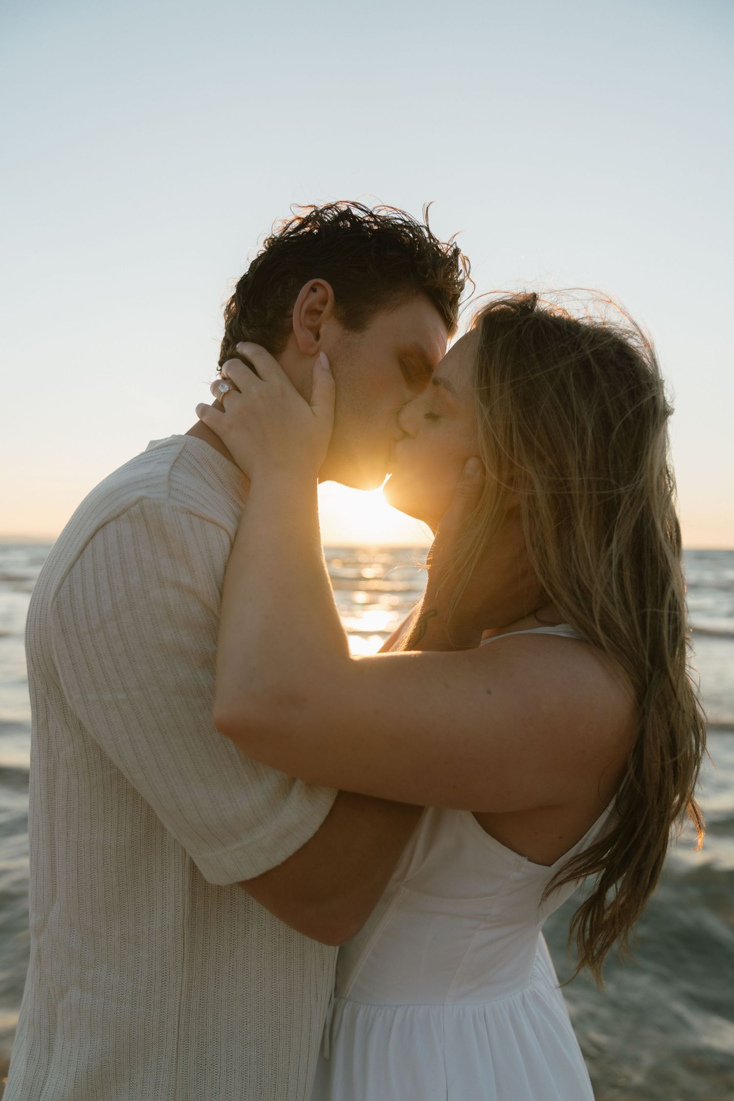 Romantic sunset beach kiss with golden light filtering through.