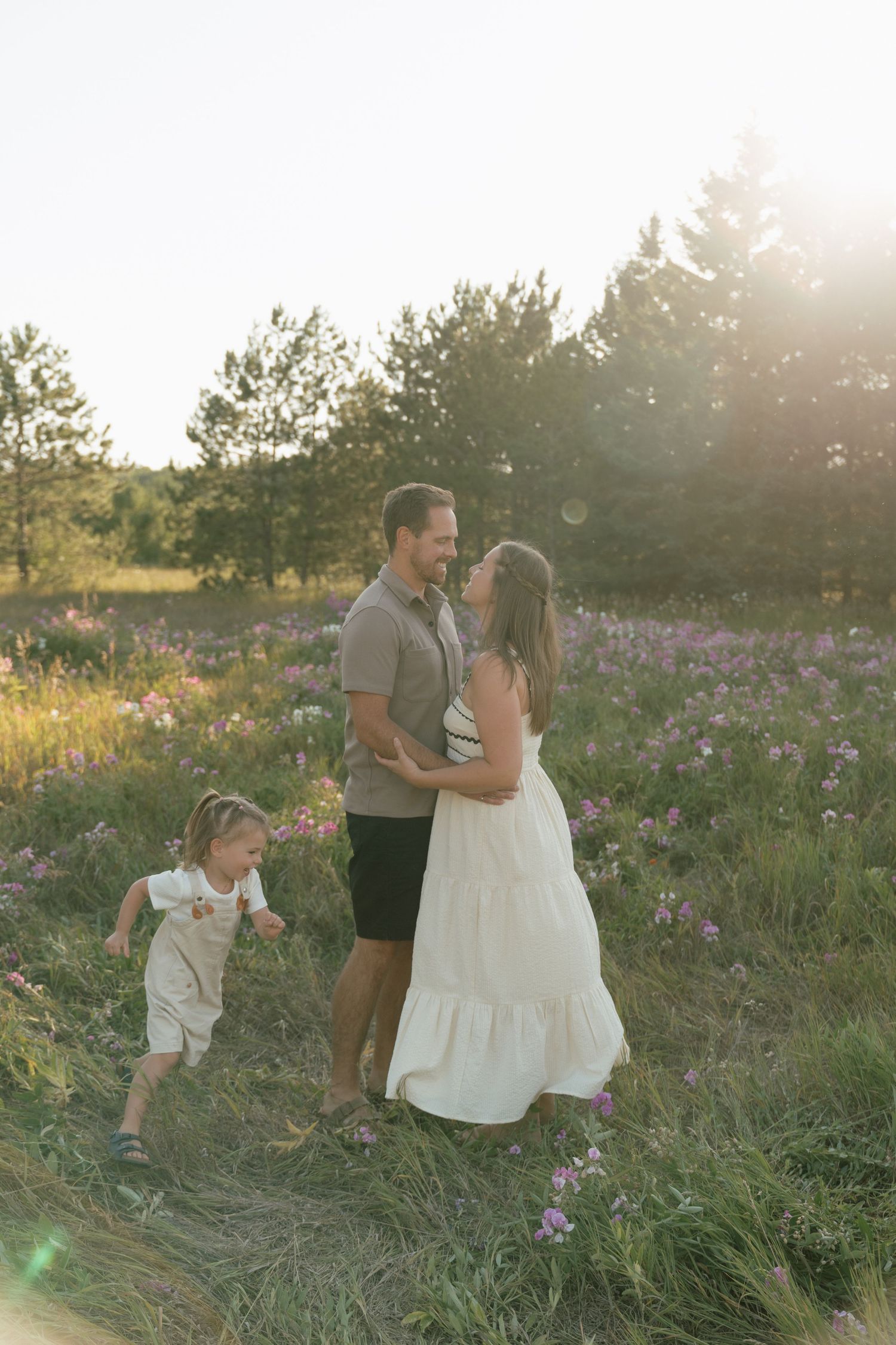 Family enjoying a playful moment together in a wildflower field at sunset.