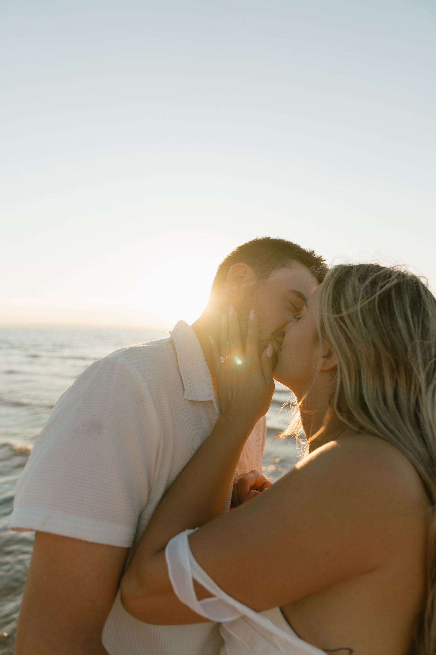 Romantic sunset beach moment with golden sunlight streaming between the couple.