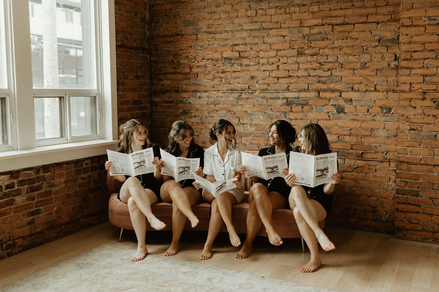 A group sitting together against a rustic brick wall in casual attire.