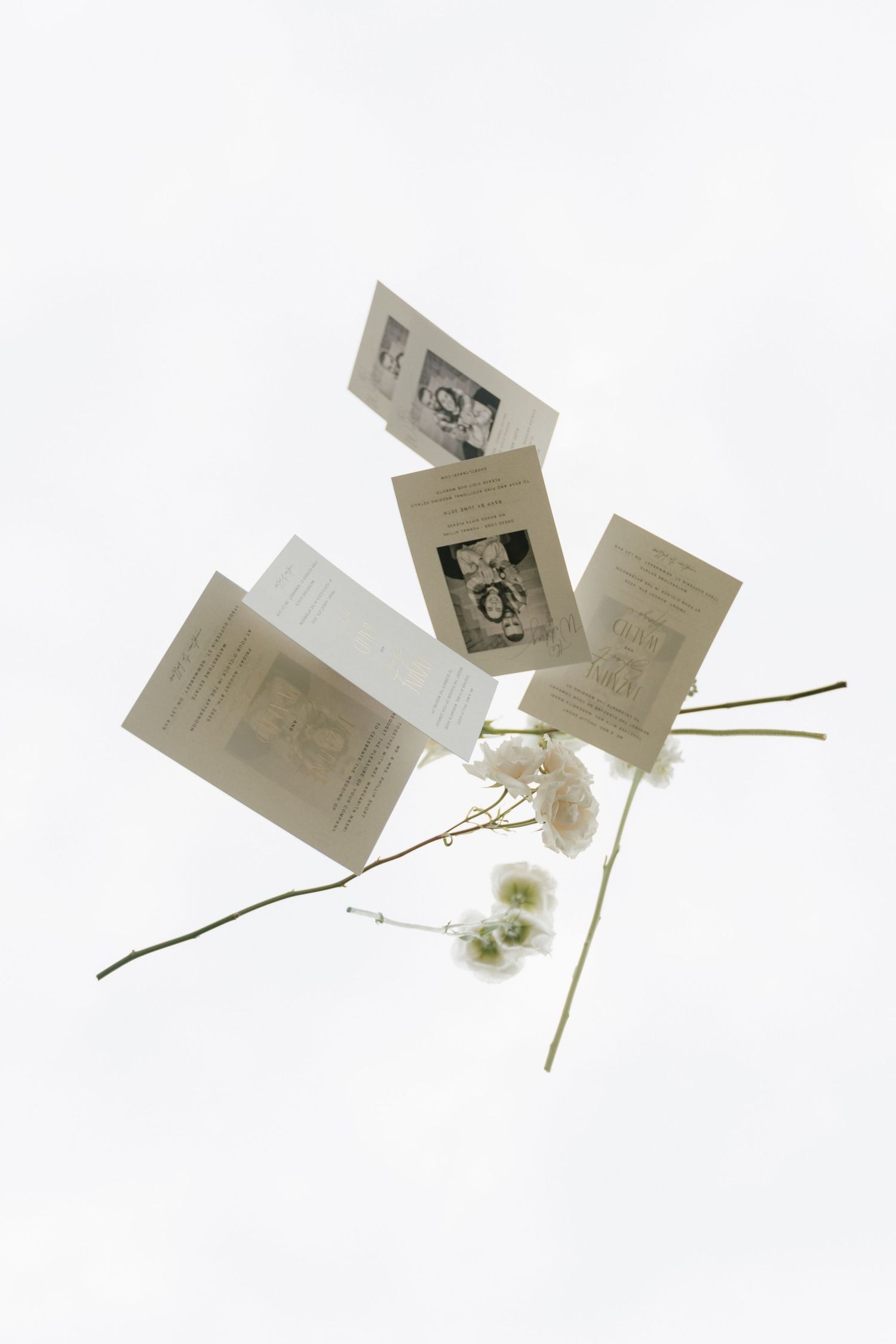 Artistic flatlay of wedding invitations with dried flowers in black and white.