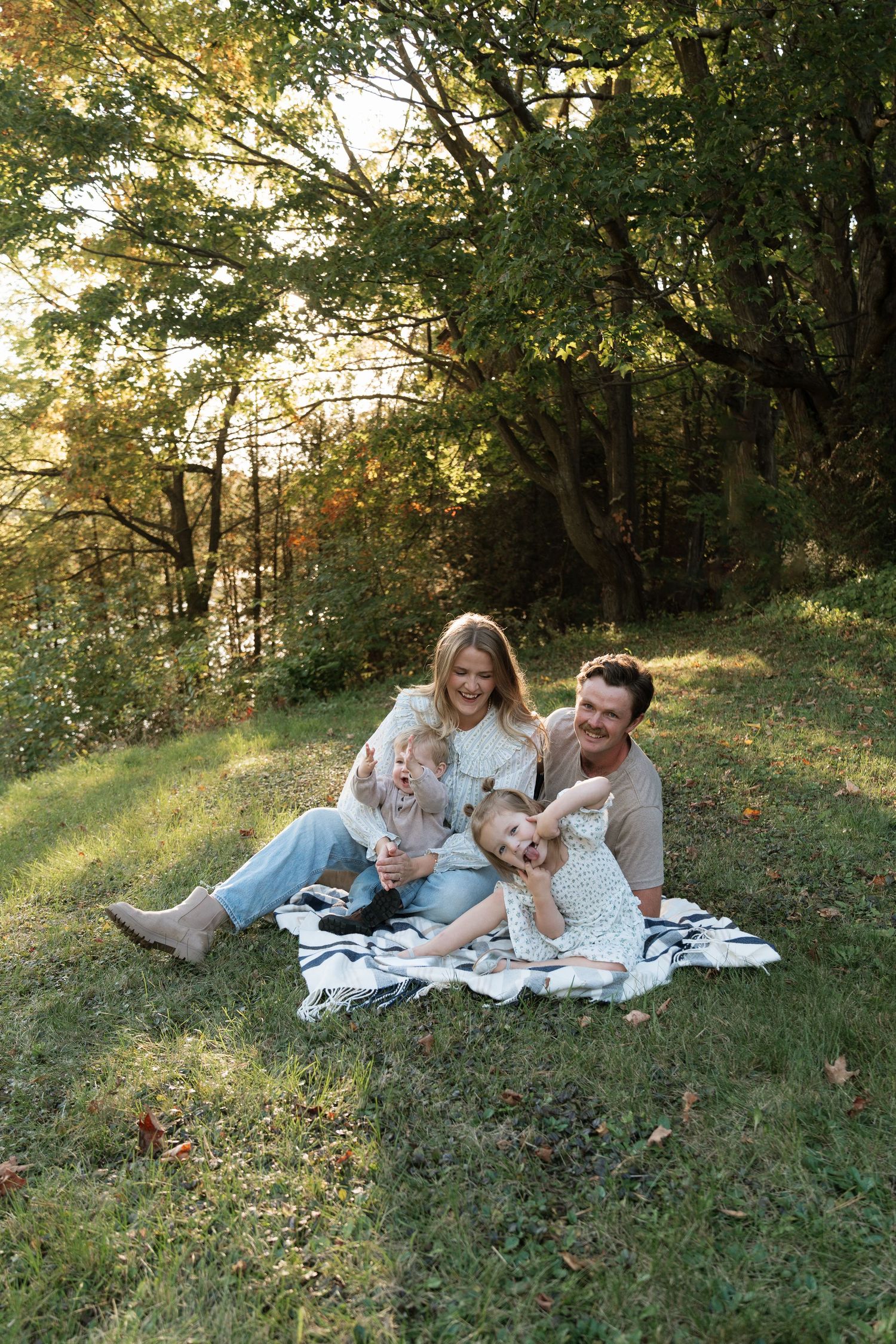 Family lying on blanket together during sunset outdoor photo session.