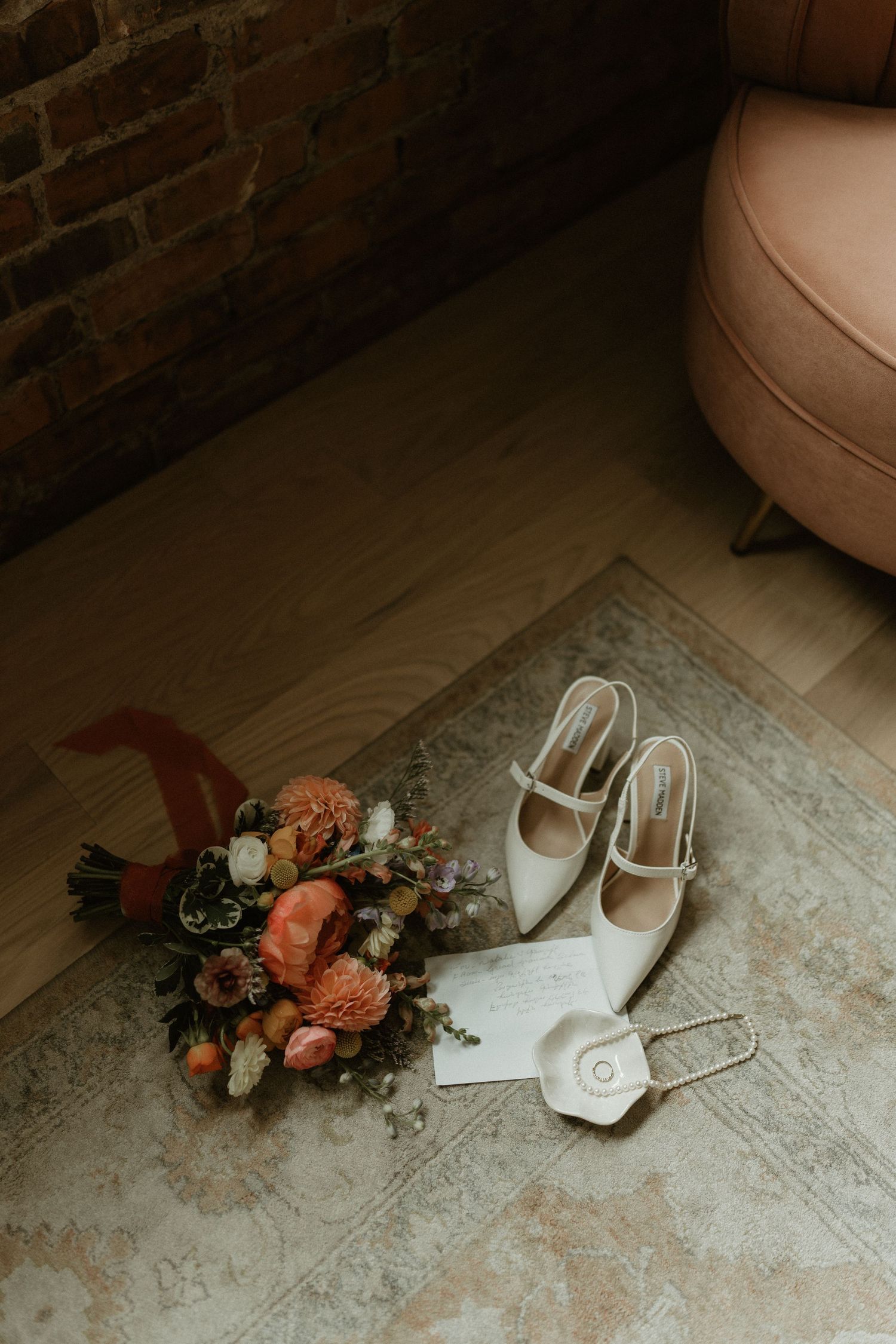 Wedding accessories including white shoes and a floral bouquet arranged on a textured floor.