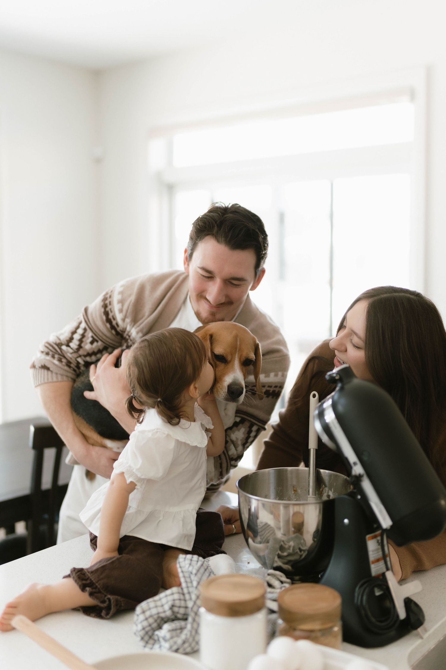 Family and dog sharing intimate moment on white couch.
