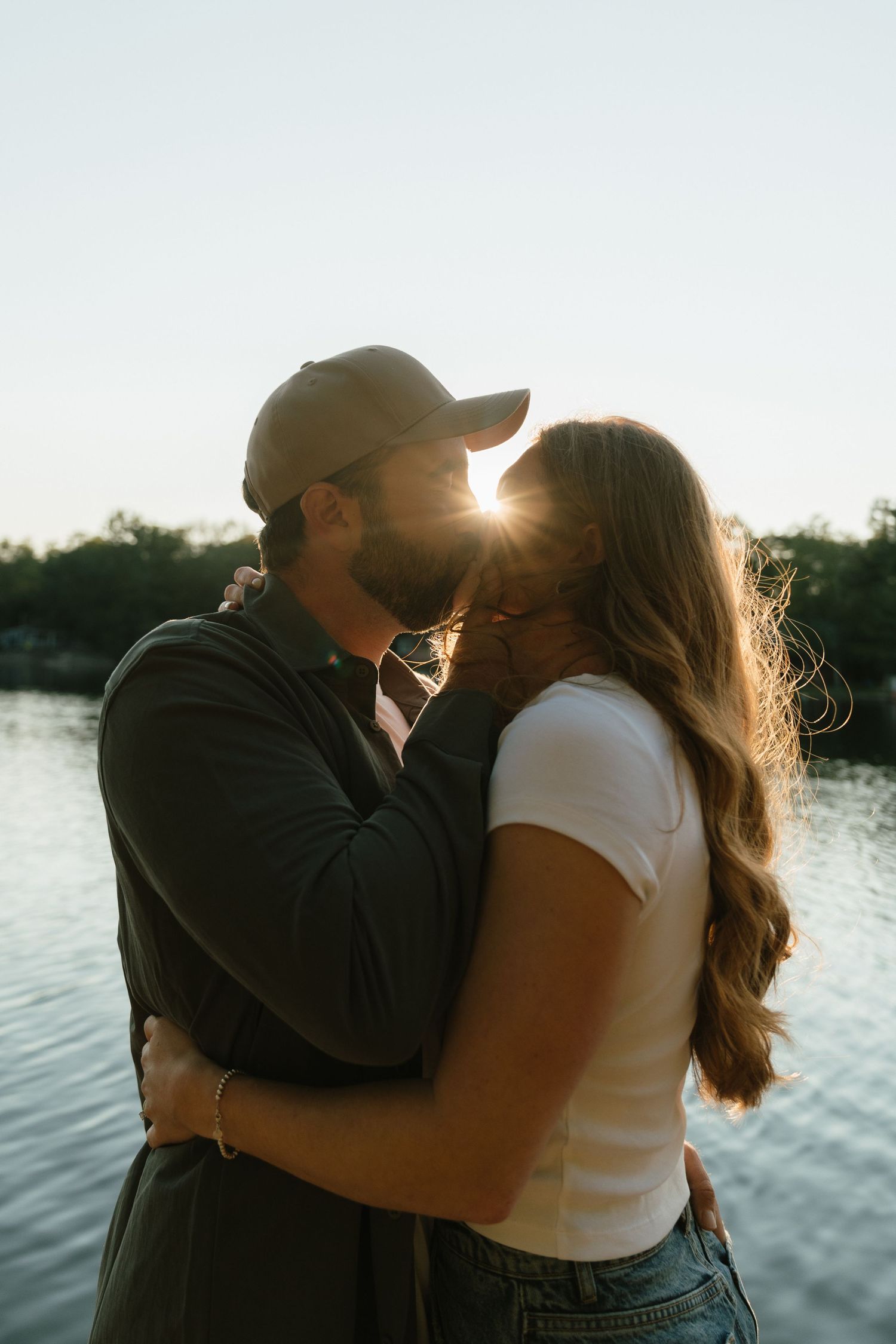 Romantic sunset silhouettes by waterfront during golden hour.