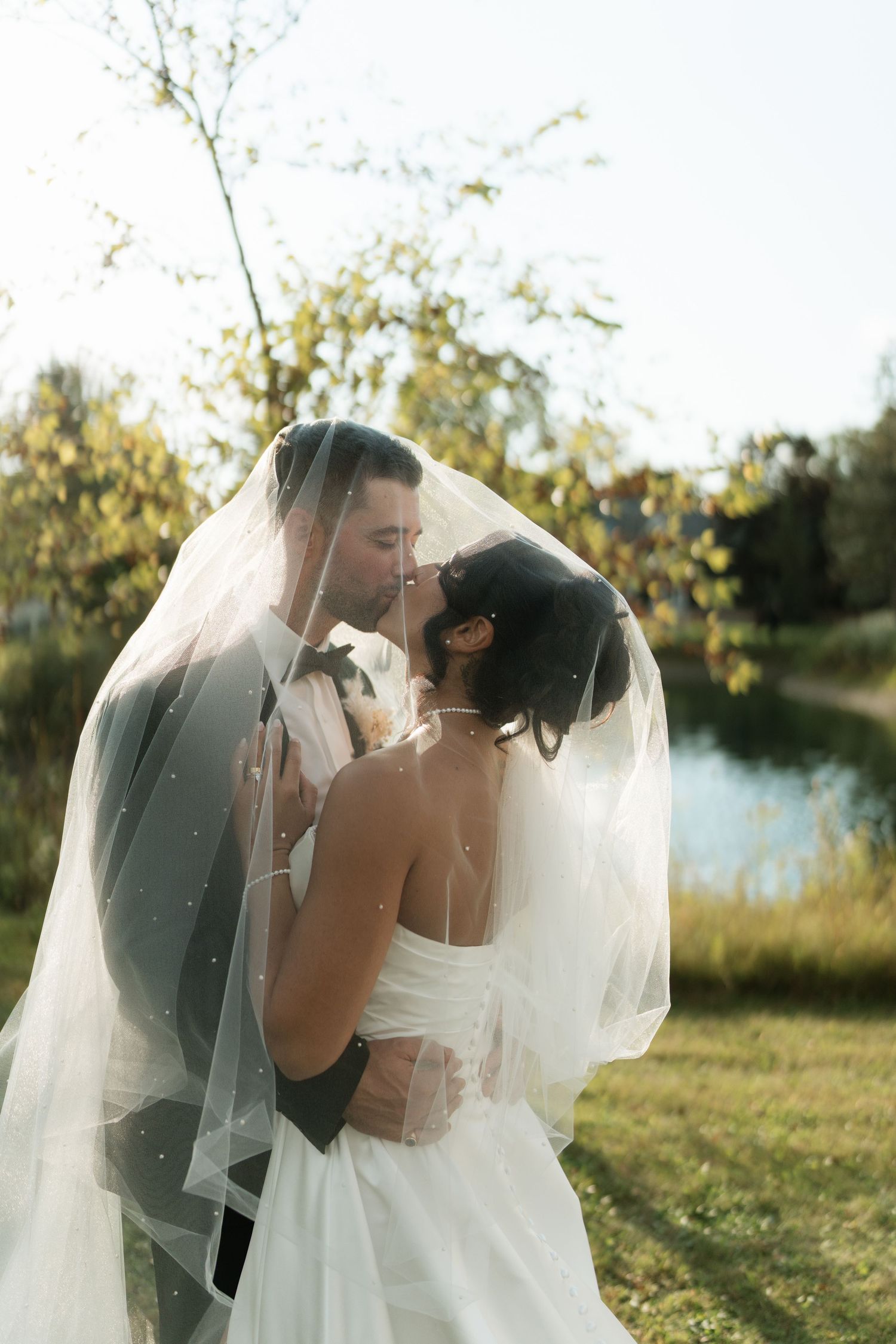 A romantic moment under a wedding veil during golden hour.