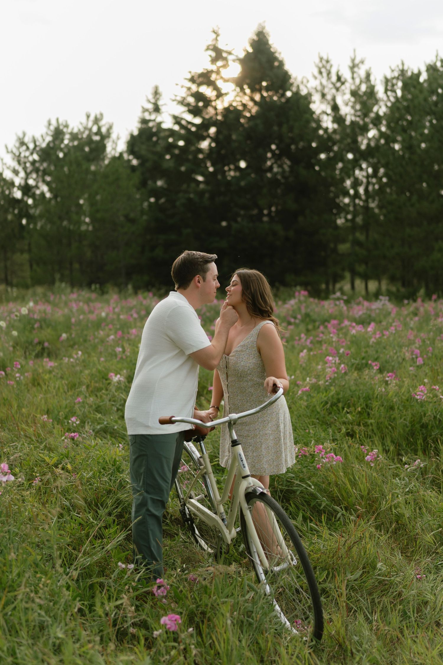 Couple sharing a romantic moment in a wildflower meadow with a vintage bicycle at golden hour.