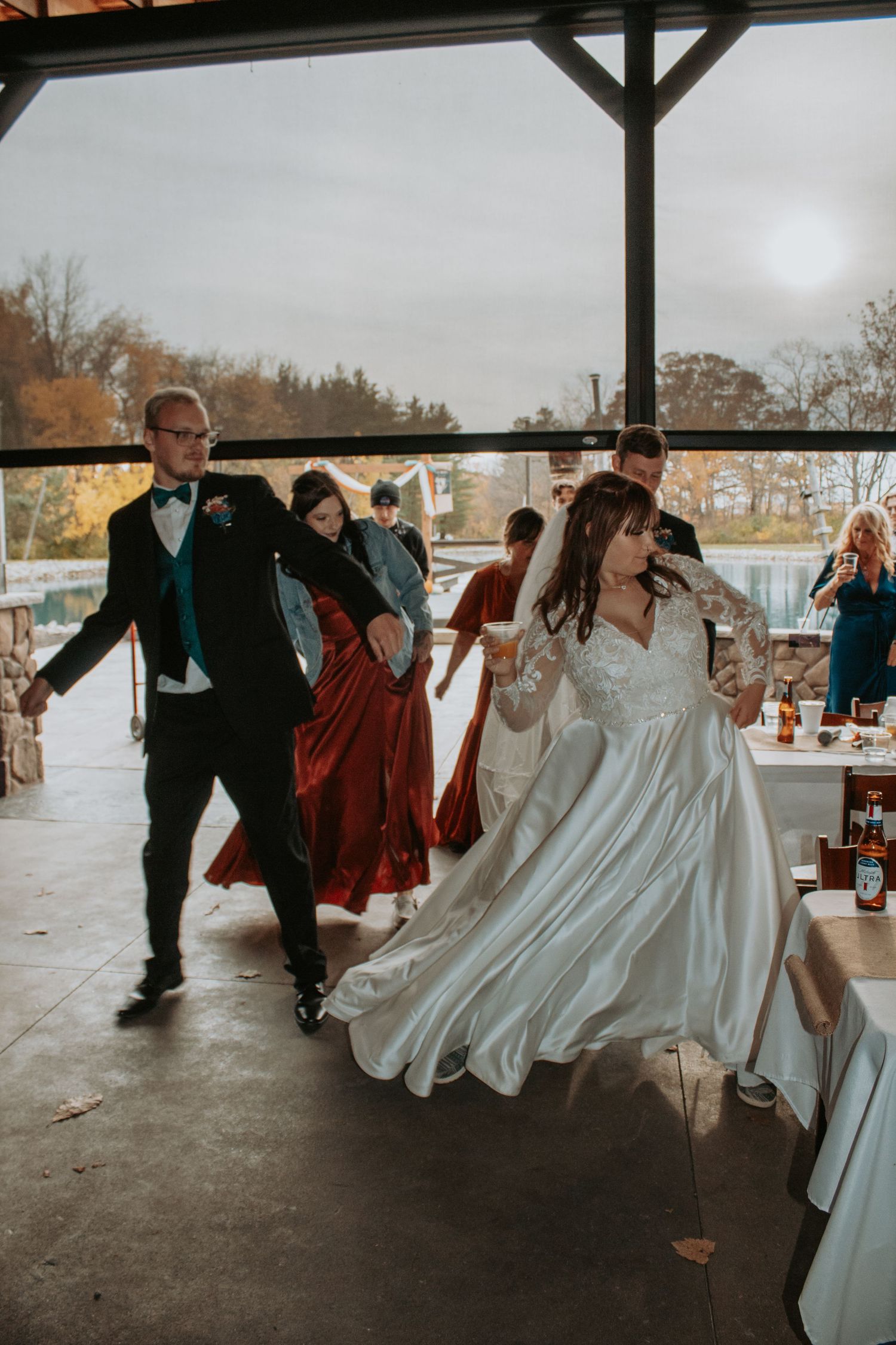 Wedding party dancing and celebrating under covered outdoor pavilion.