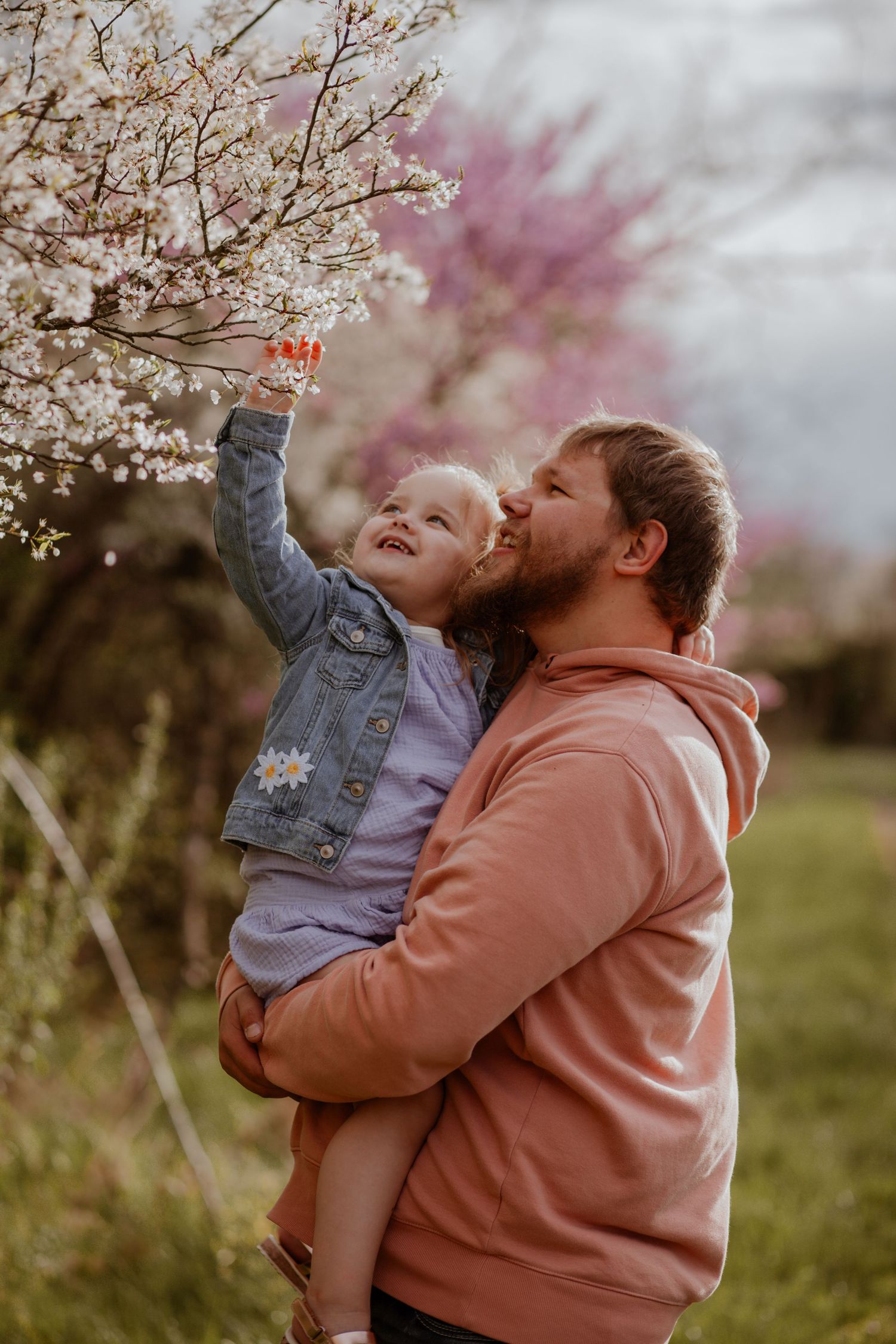 Joyful interaction beneath blooming spring trees in natural setting.
