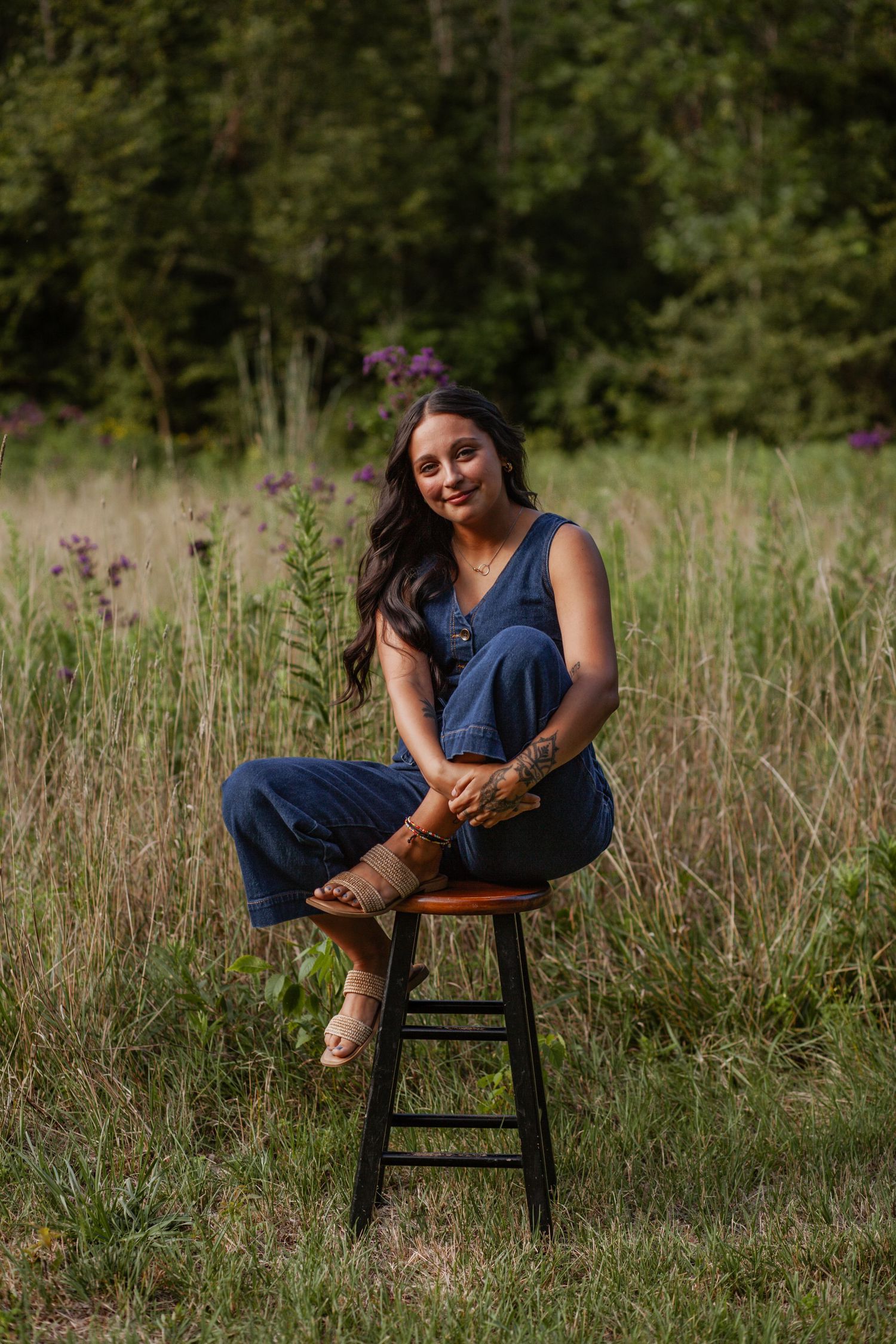 Rustic outdoor portrait session with wooden chair in tall grass field.