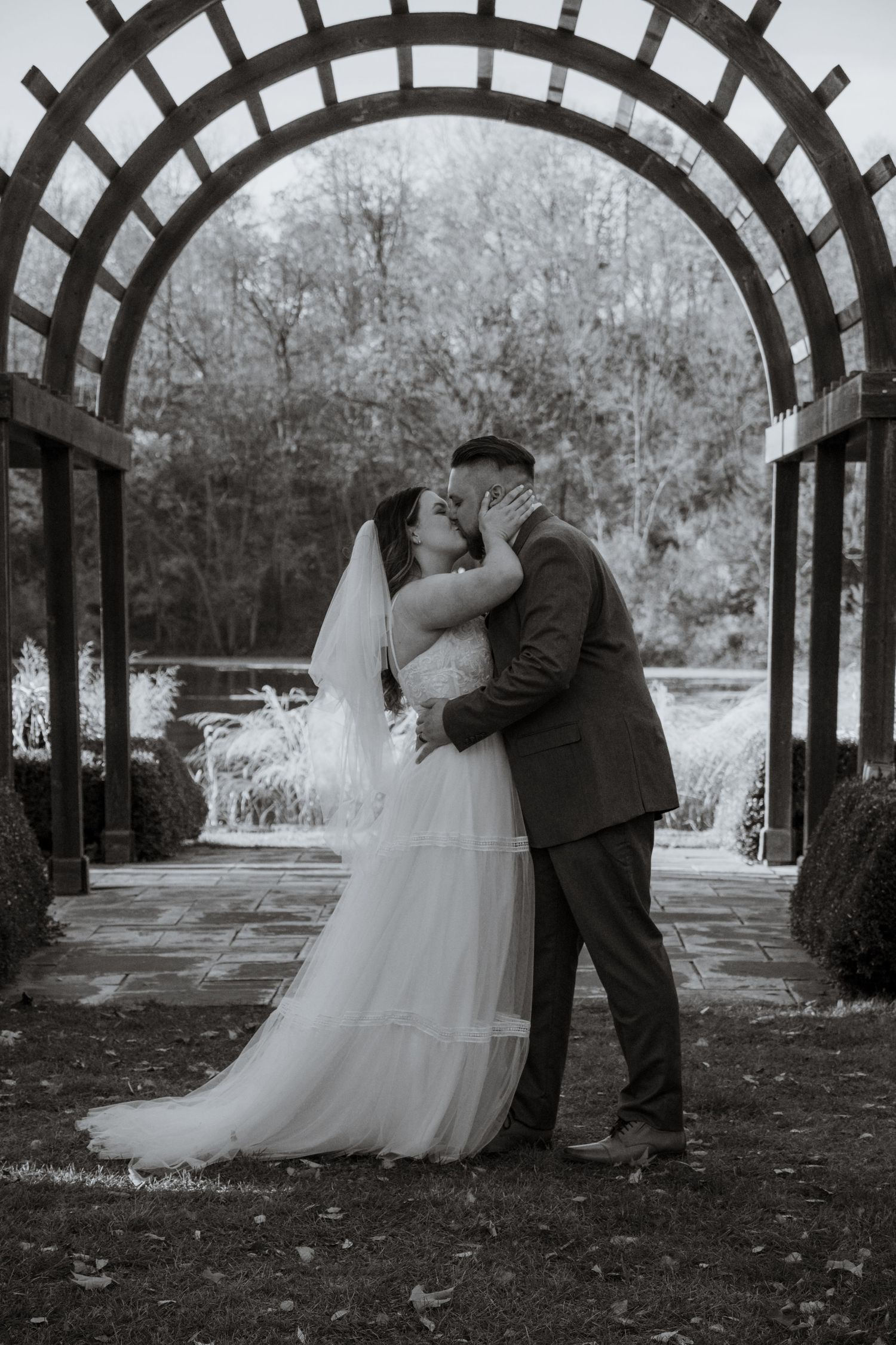 Romantic wedding photos taken under a wooden garden arbor walkway.