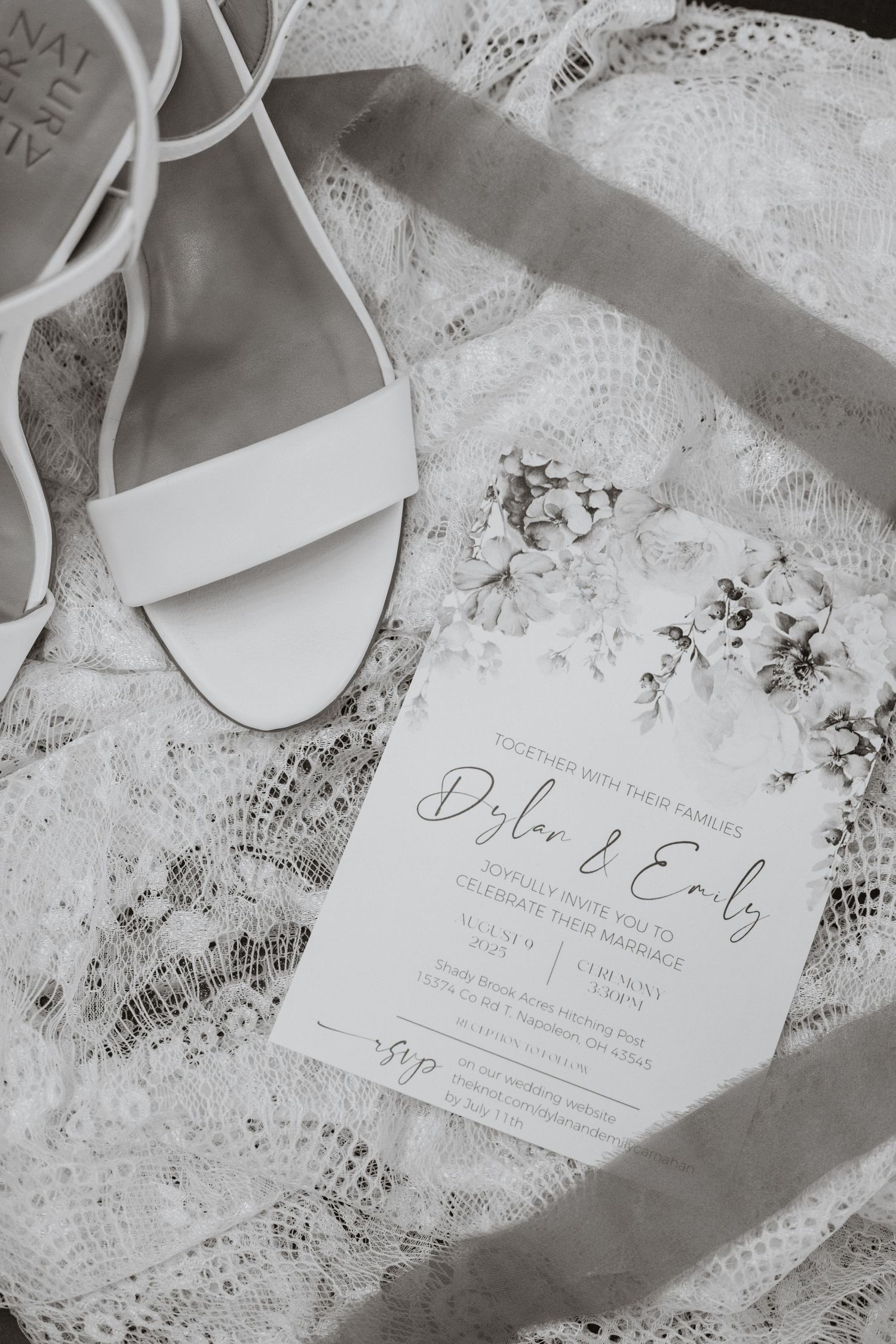 Wedding invitation with white shoes and lace details in black and white.