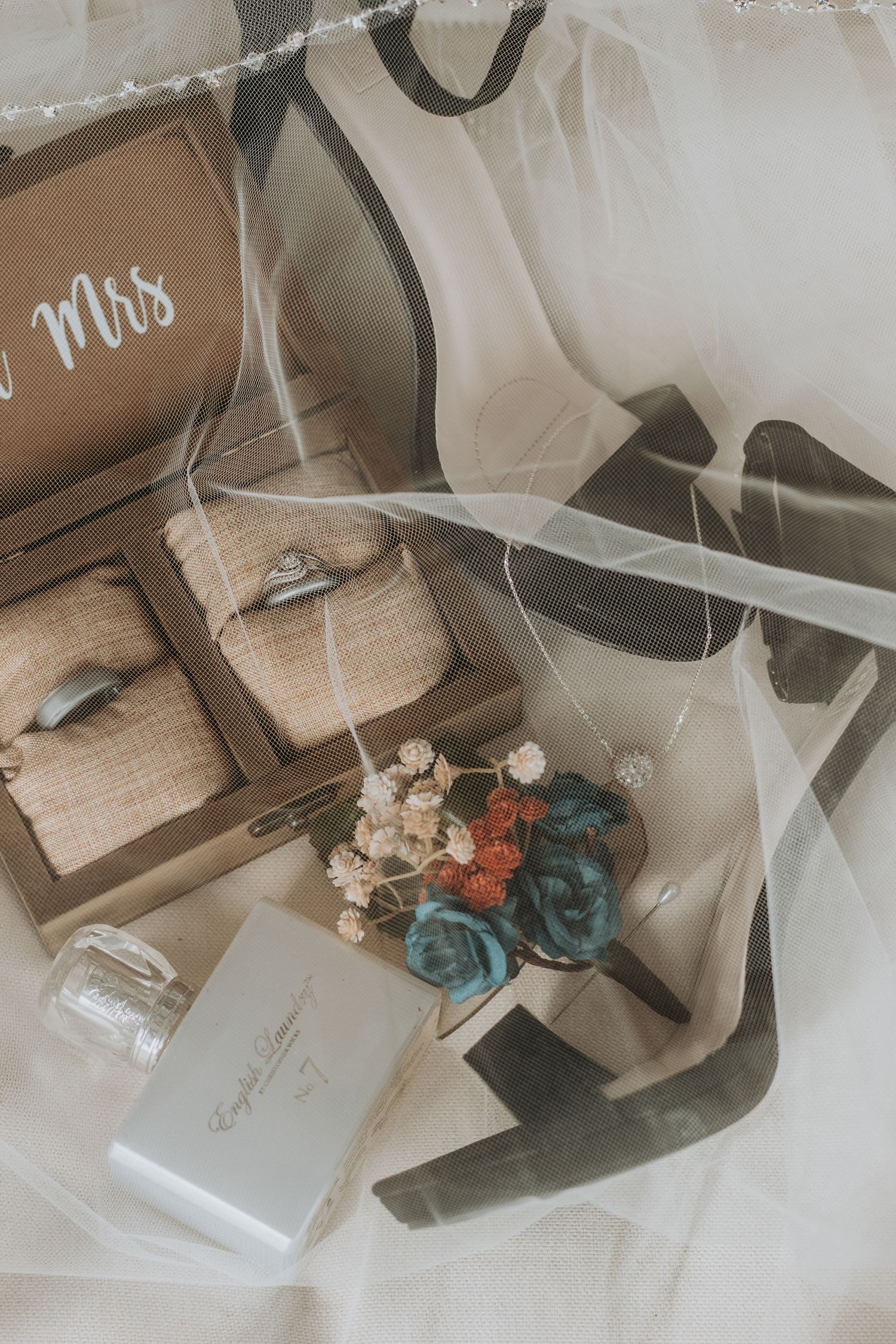Wedding accessories and decor with blue and coral flowers on white fabric.