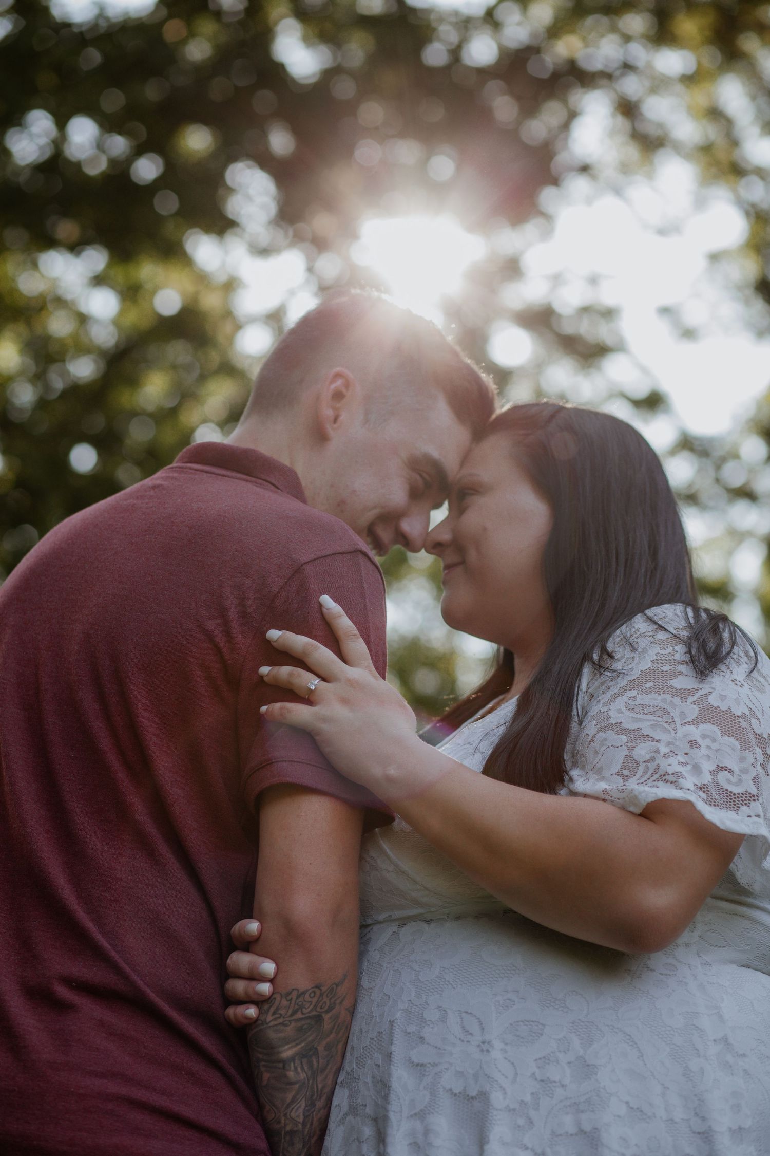 Romantic sunset portrait of couple embracing outdoors with bokeh lighting effects.