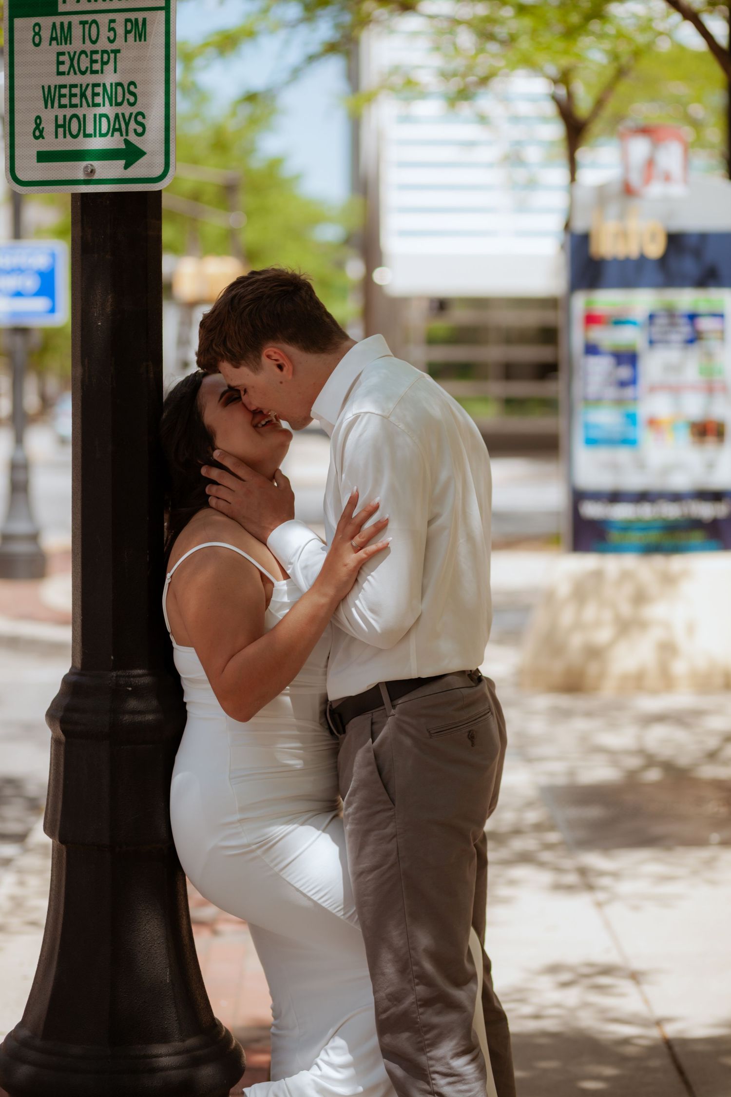 Couple in wedding attire sharing intimate moments near urban street signs.