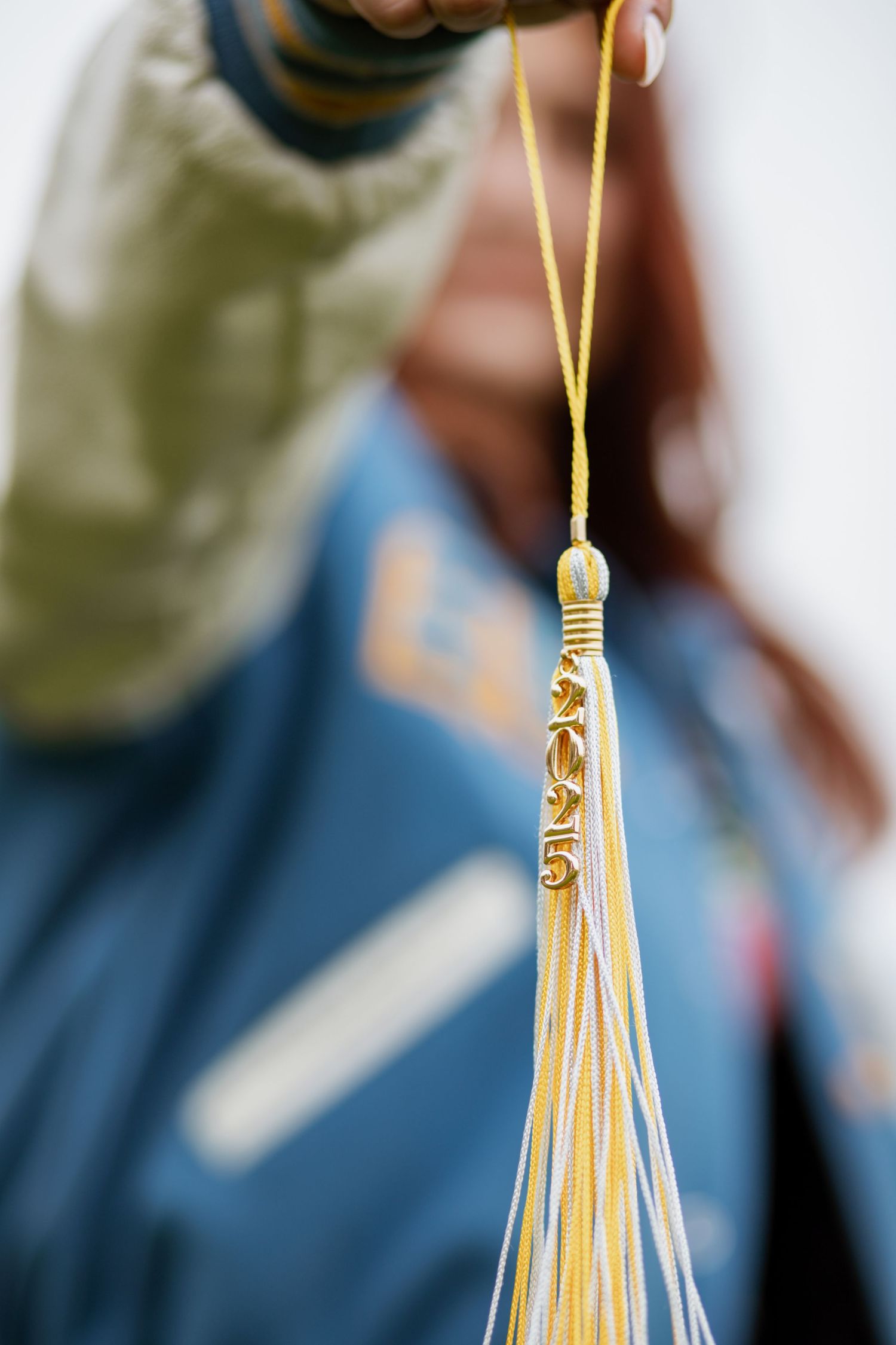 Close-up detail of gold graduation tassel against blurred background.