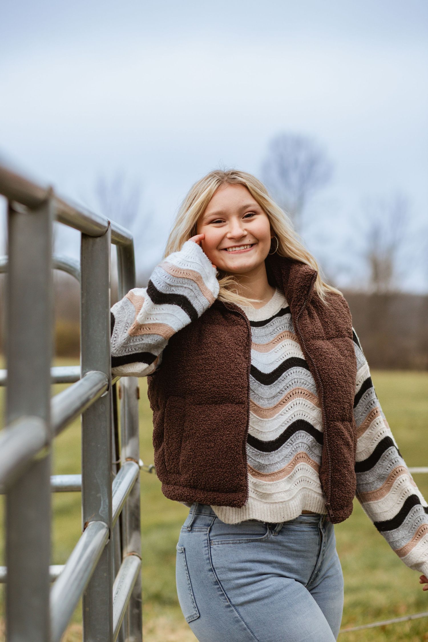 A series of photos showing someone in a brown and white striped sweater posing against a wooden fence in a rural setting.