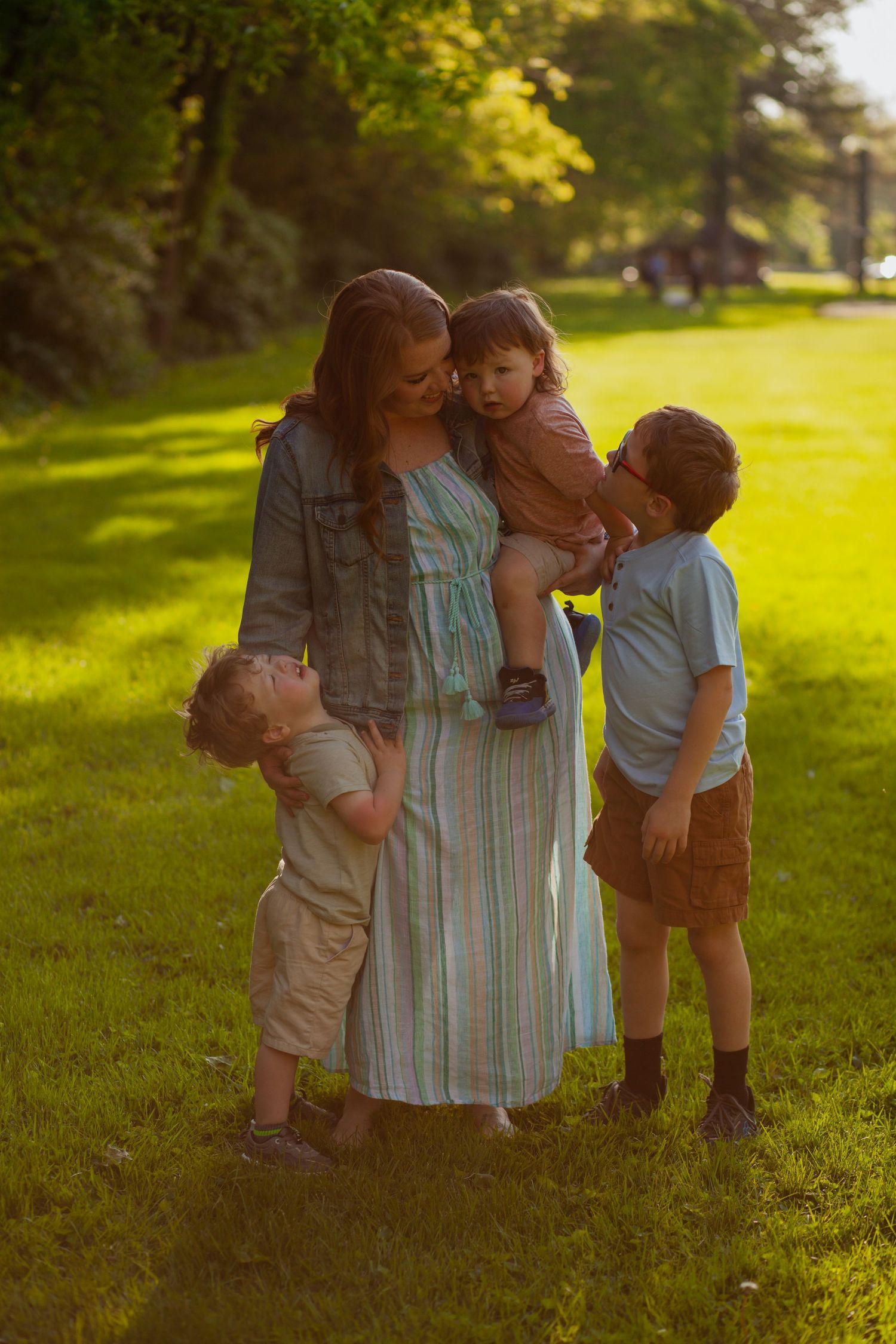Family portrait in a sunlit park during golden hour.