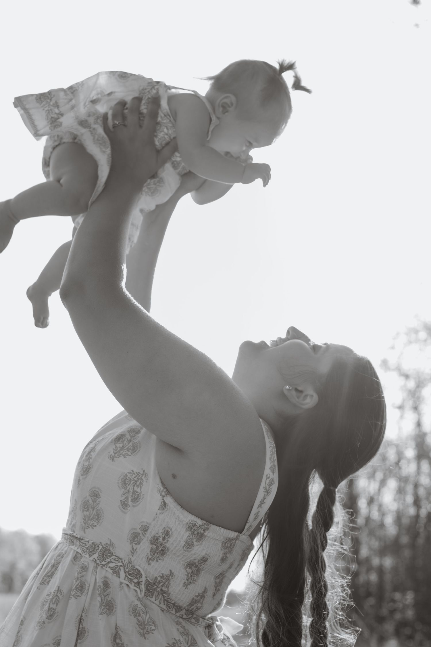 Black and white sequence of a parent joyfully lifting a baby in the air.
