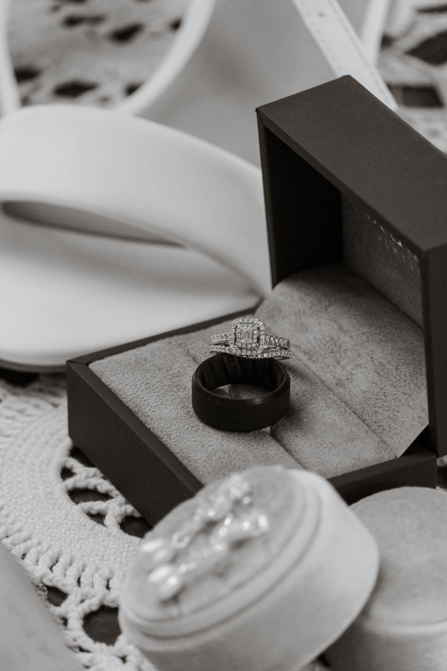 Wedding rings and jewelry photographed on textured gray surfaces with dramatic lighting.