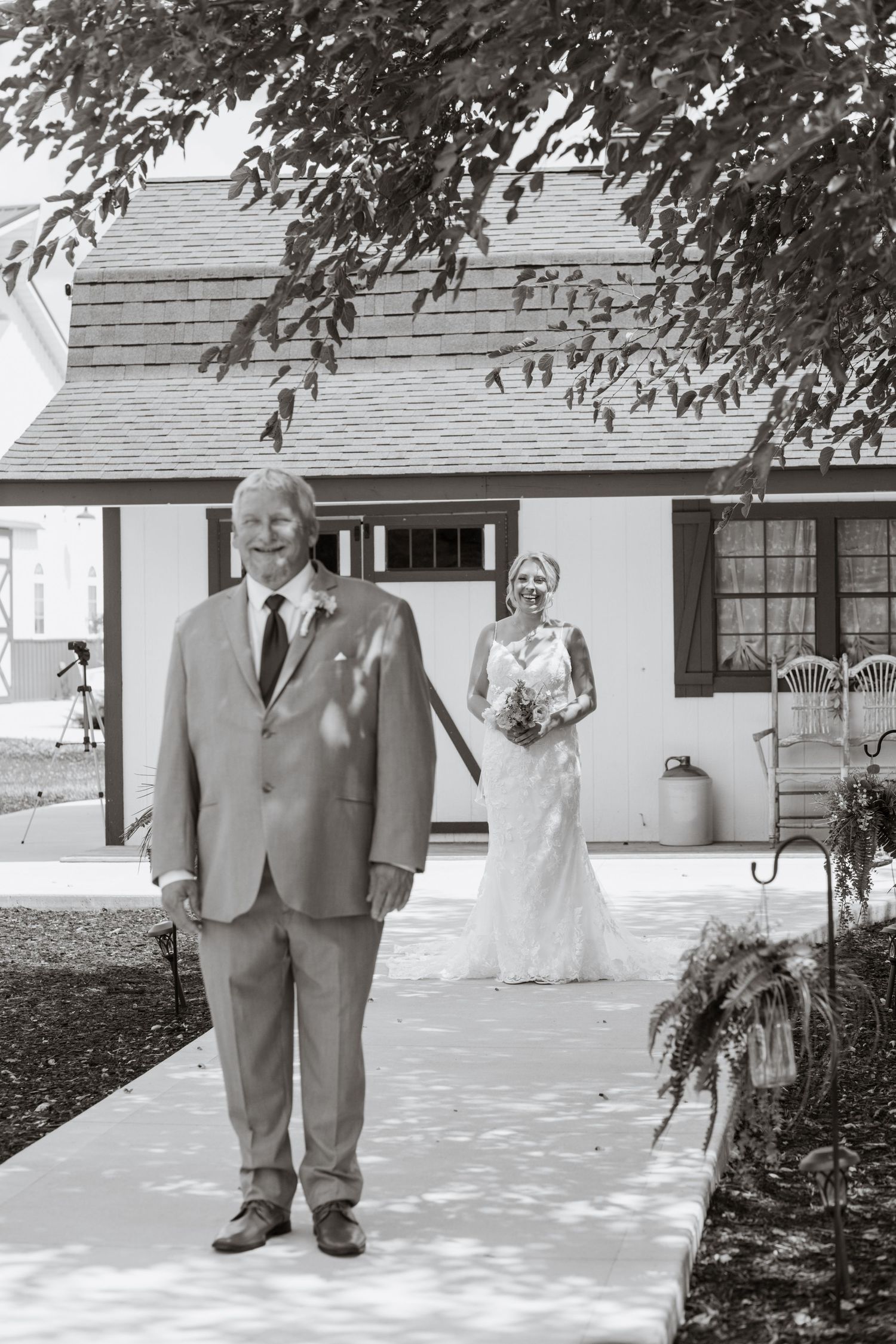 Black and white photo of a wedding day first look moment outside a white cottage.